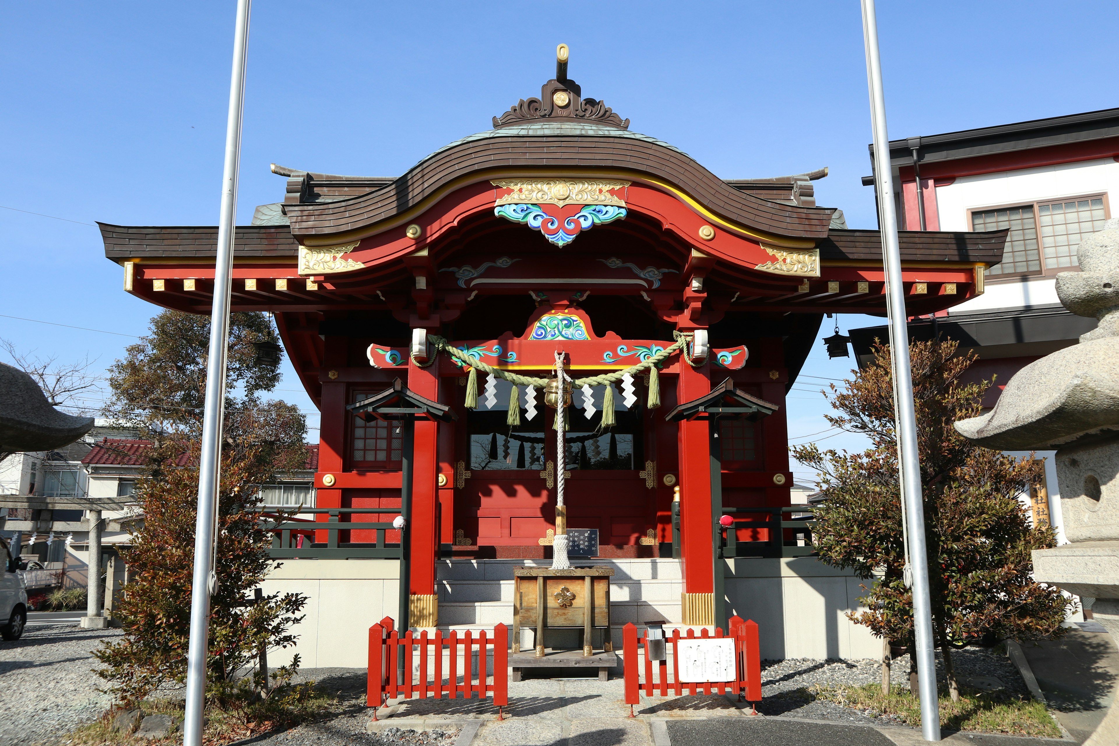 一座红色屋顶的神社建筑，周围有树木