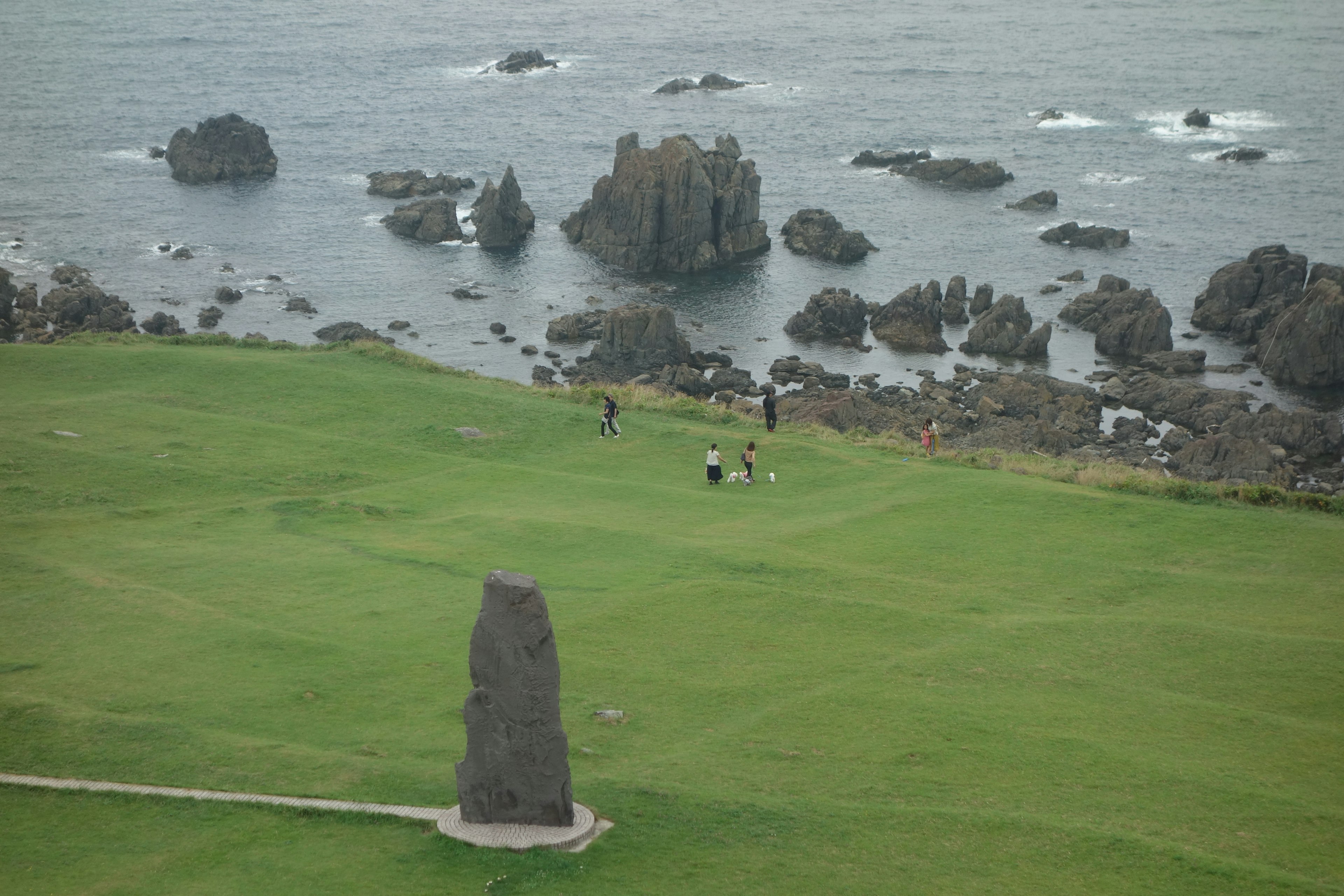 View of a large stone monument on green grass by the coast