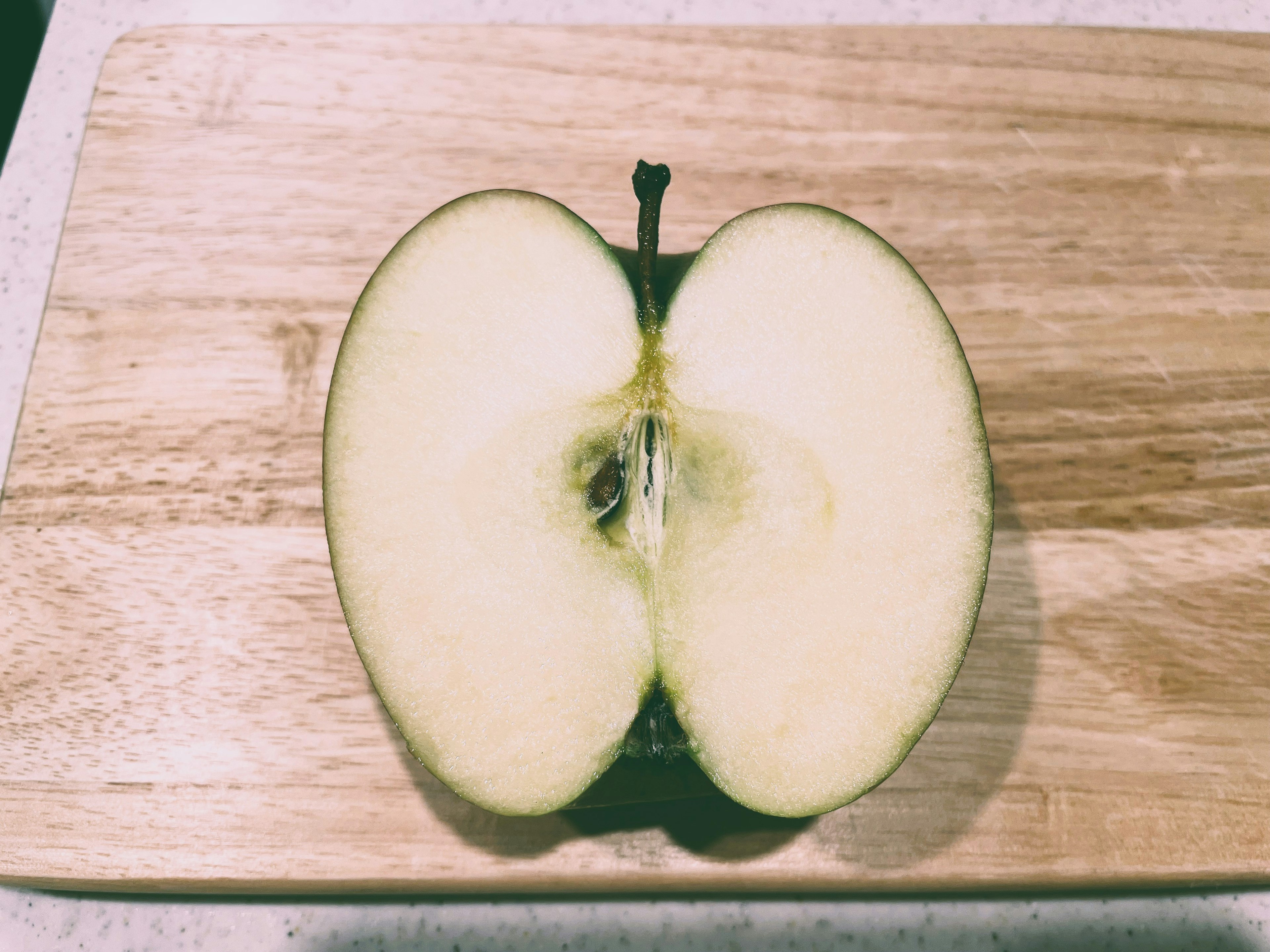 Moitié d'une pomme verte sur une planche à découper en bois