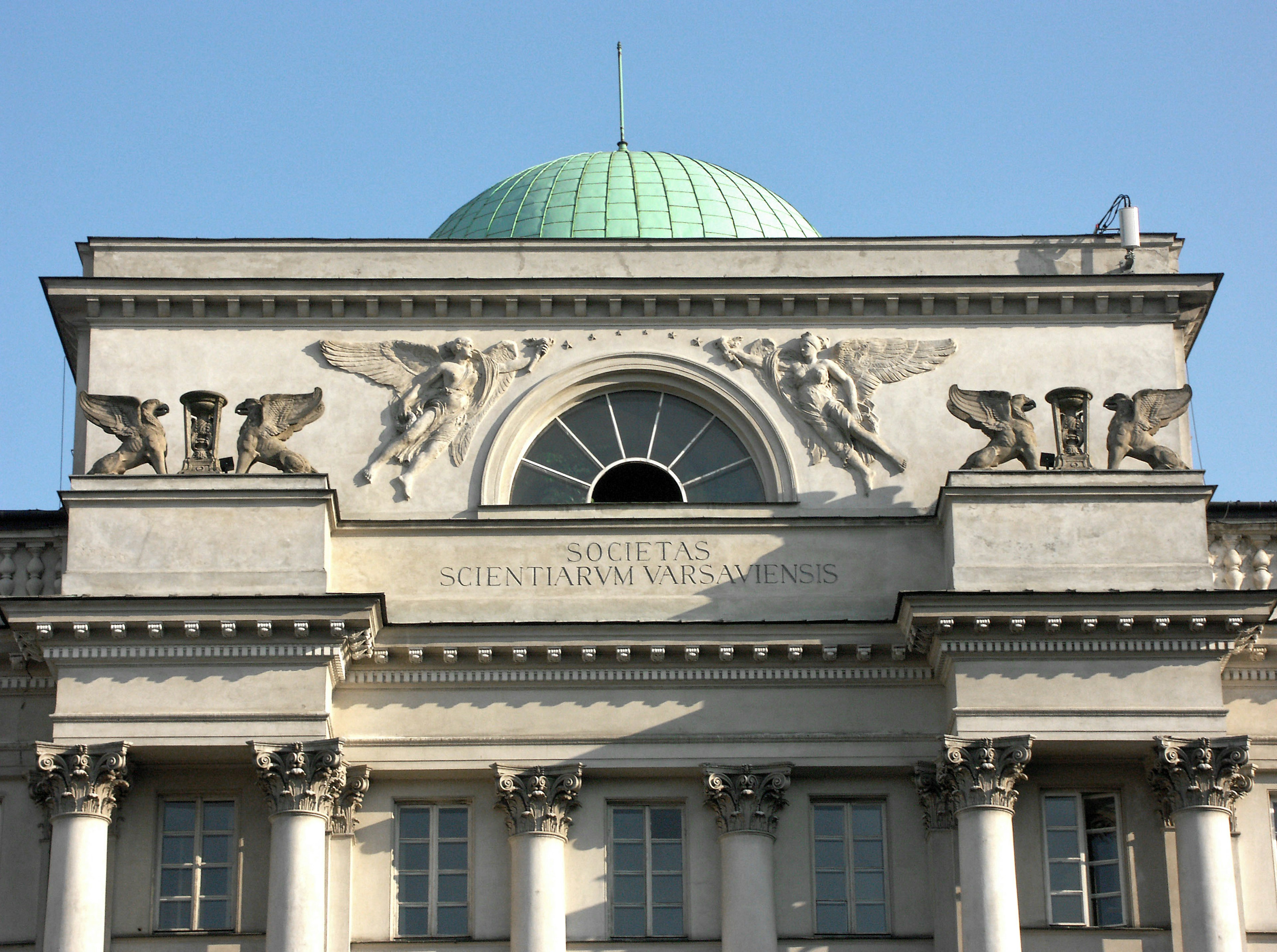 Facade of a grand building featuring a green dome and decorative sculptures