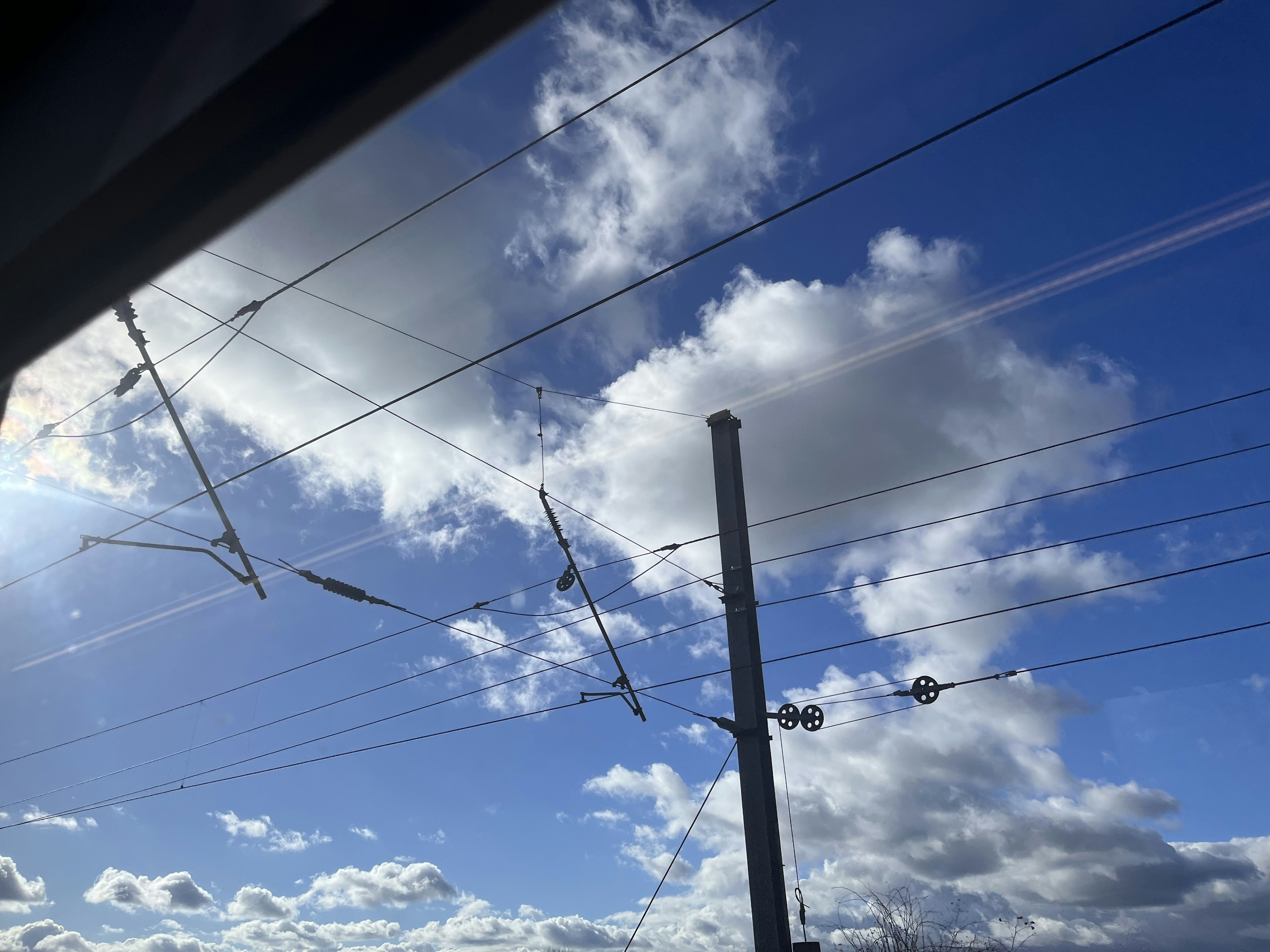 View of blue sky with white clouds and railway overhead lines