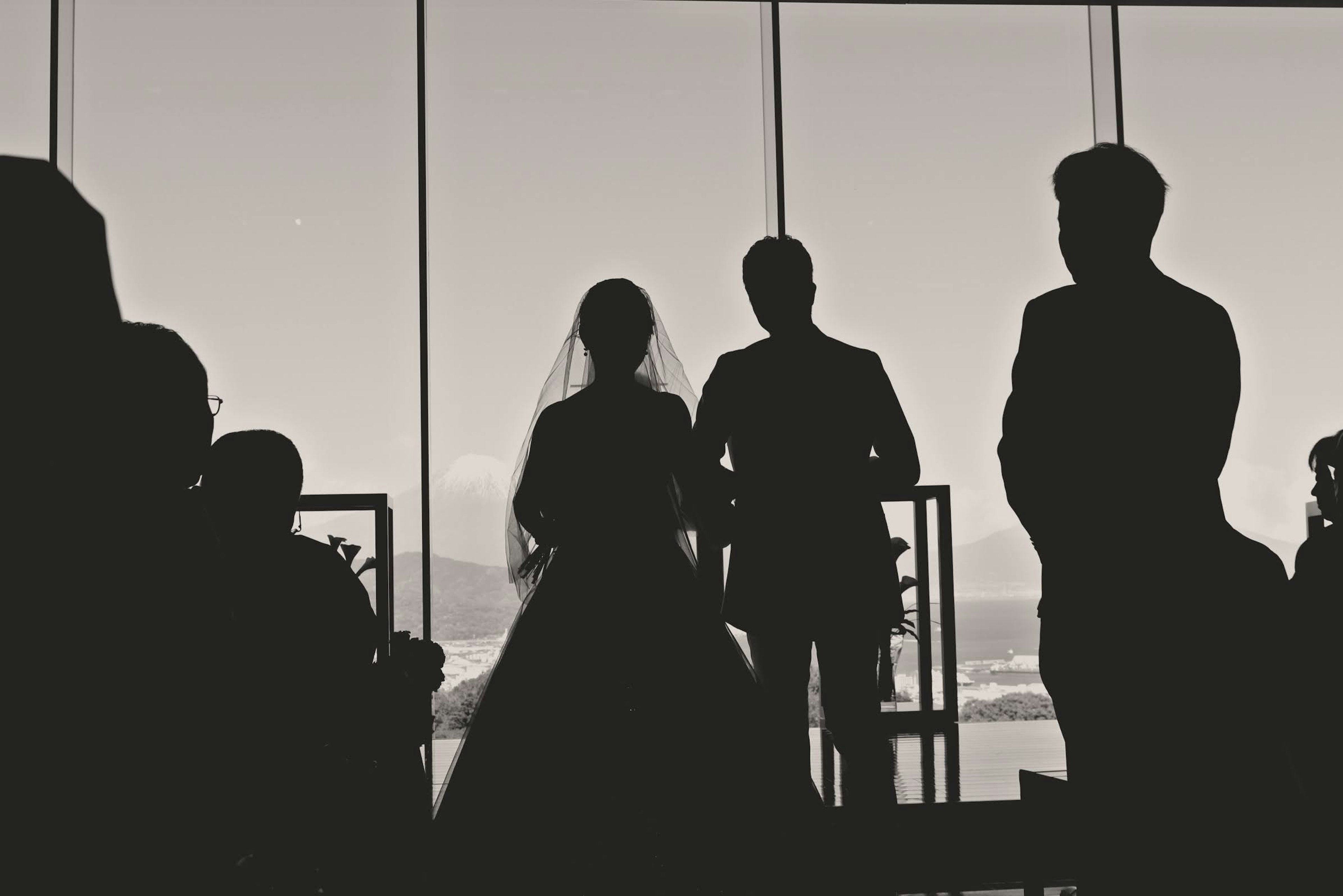 Silhouette of a wedding ceremony, bride and groom, window backdrop, guests in attendance