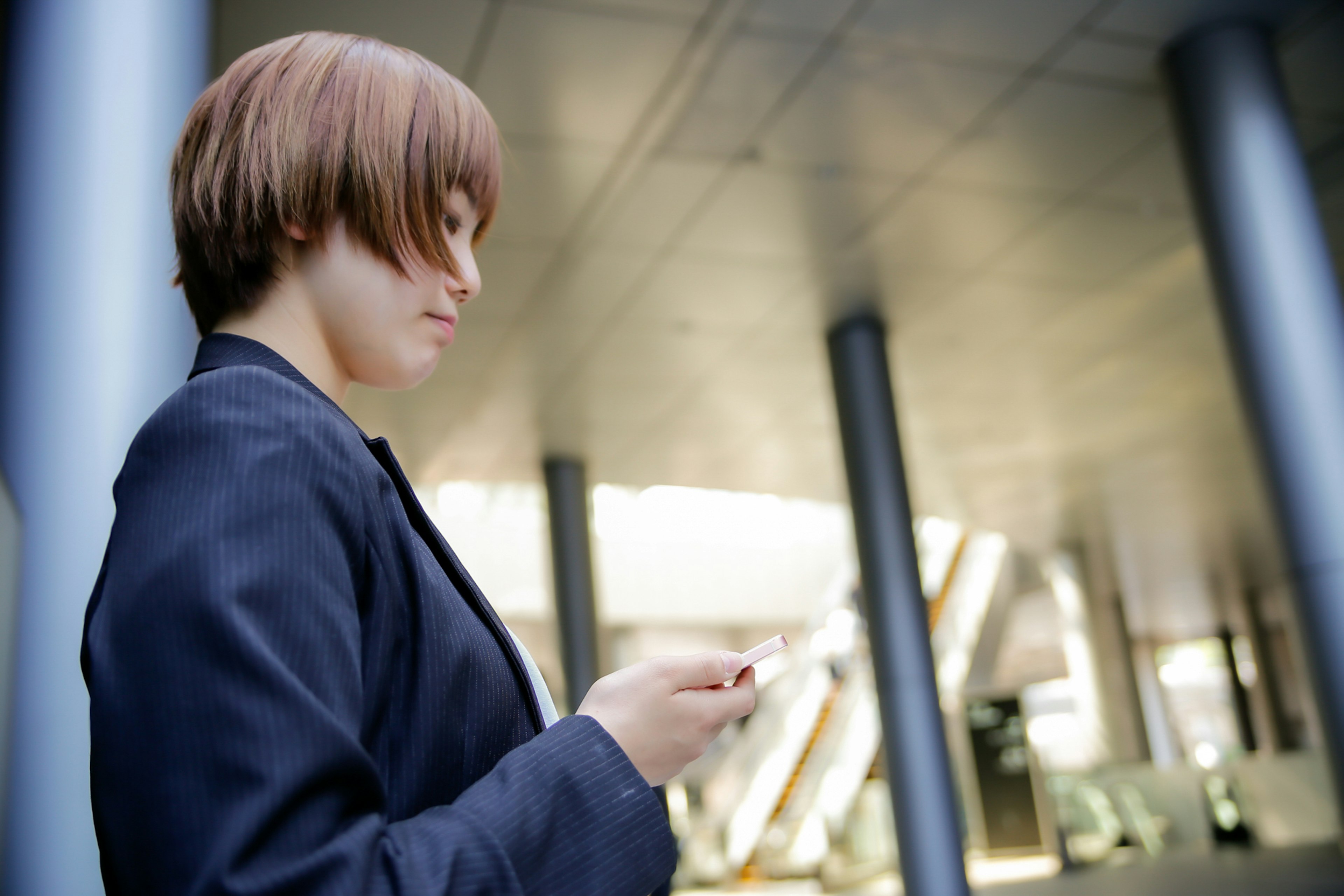 A woman in a business suit using a smartphone outdoors