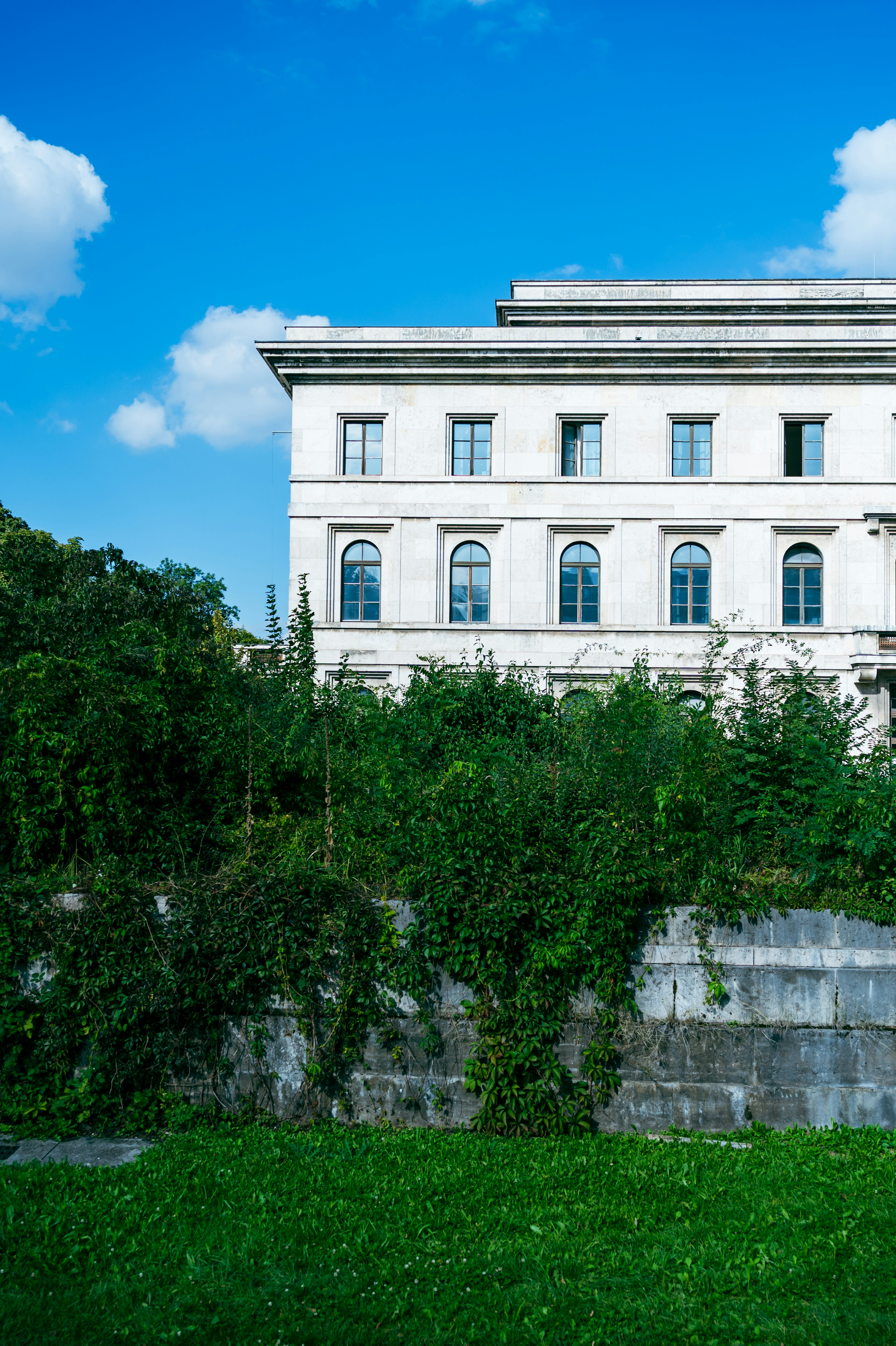 Old building surrounded by greenery with blue sky and white clouds