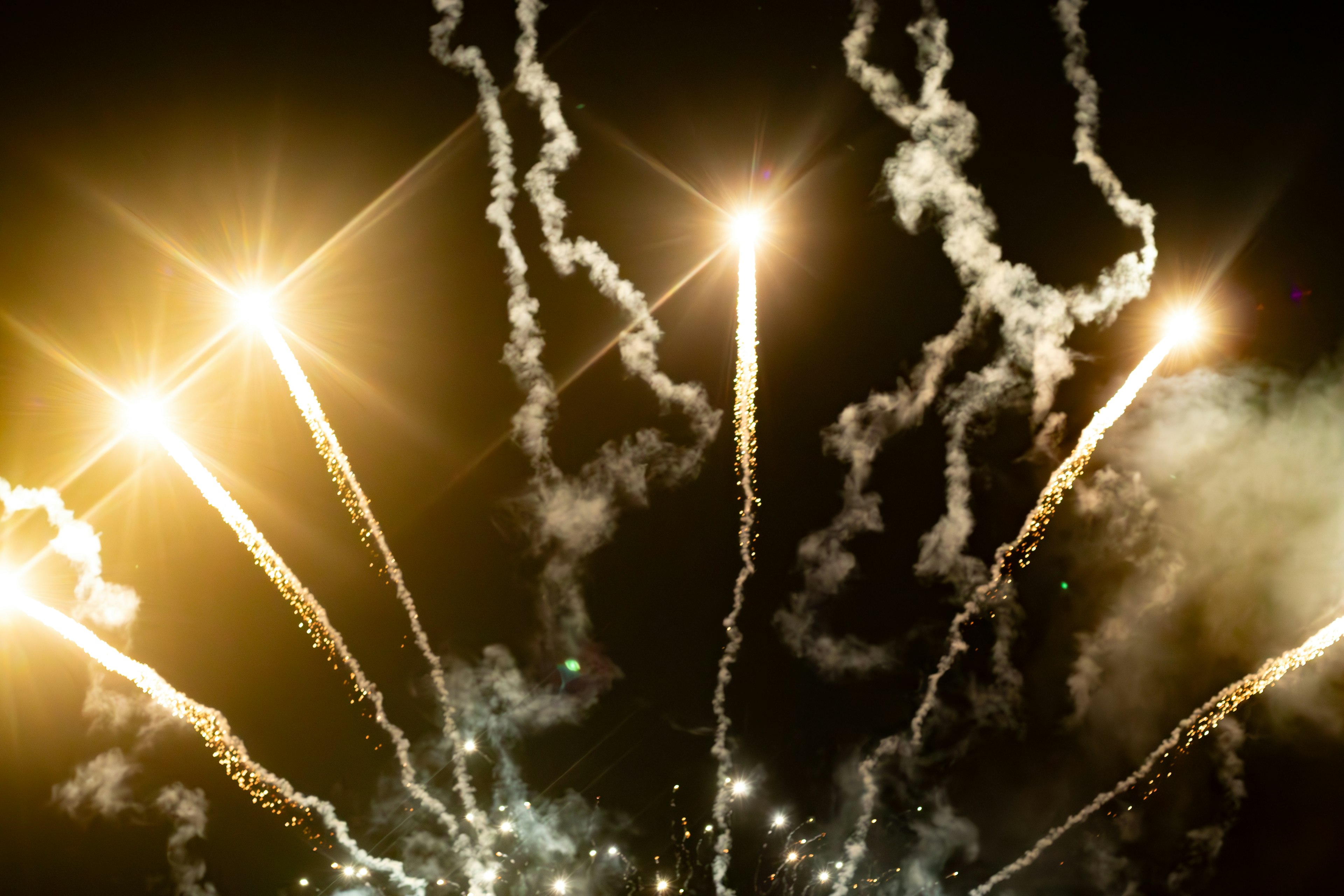 Fuegos artificiales estallando en el cielo nocturno con estelas brillantes