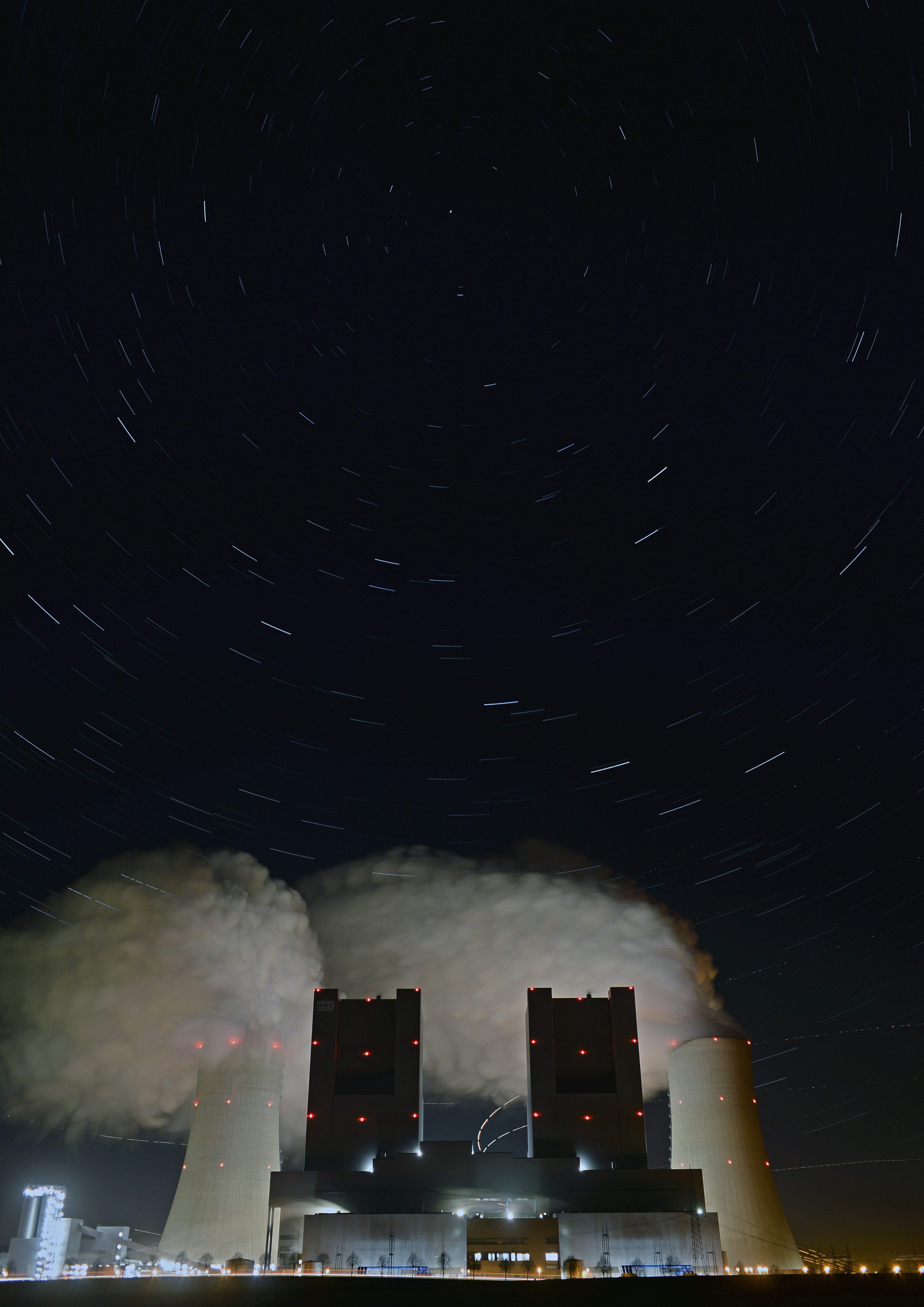 Power plant with cooling towers emitting steam under a starry night sky