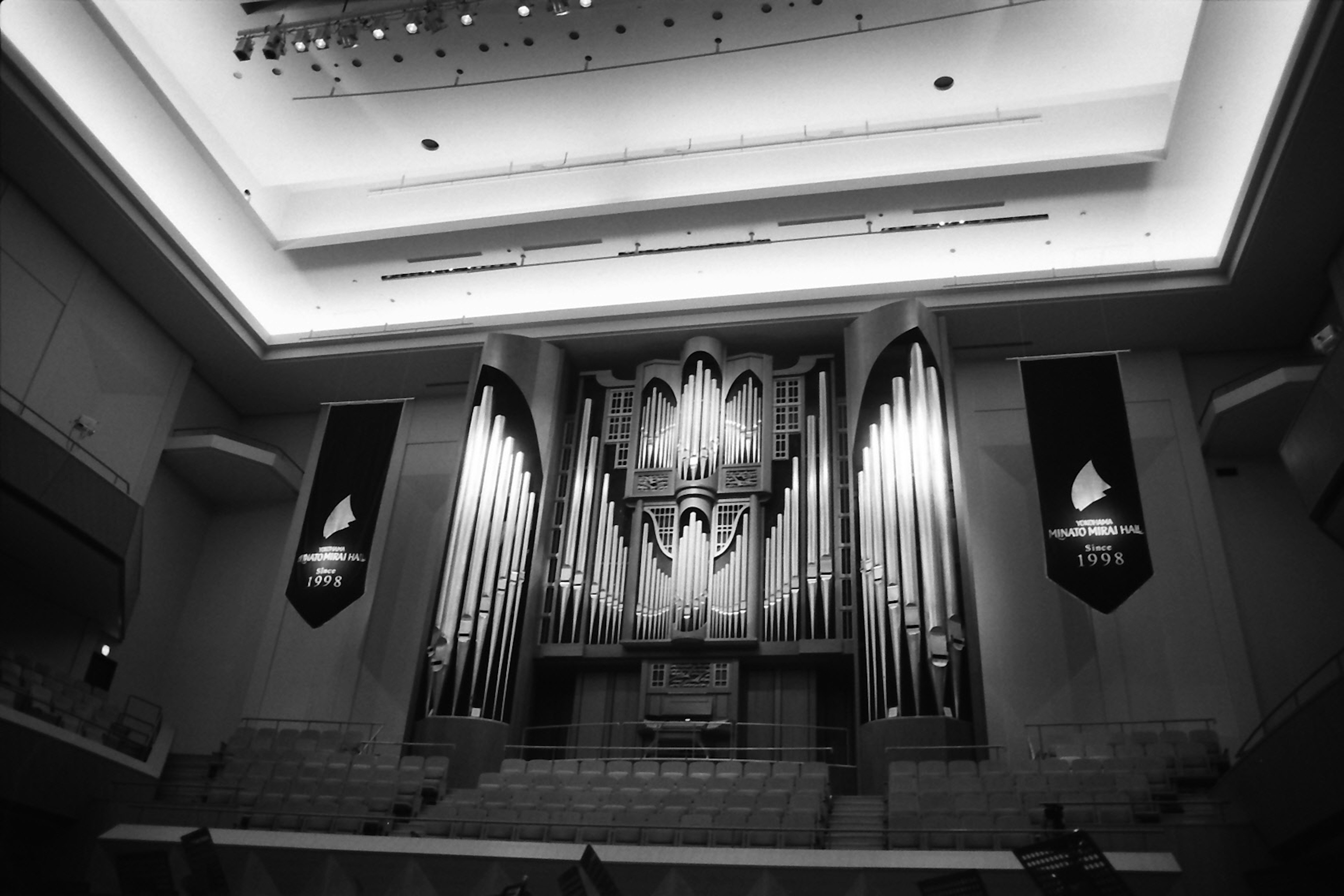 Black and white interior of a cathedral featuring a pipe organ and ceiling lighting