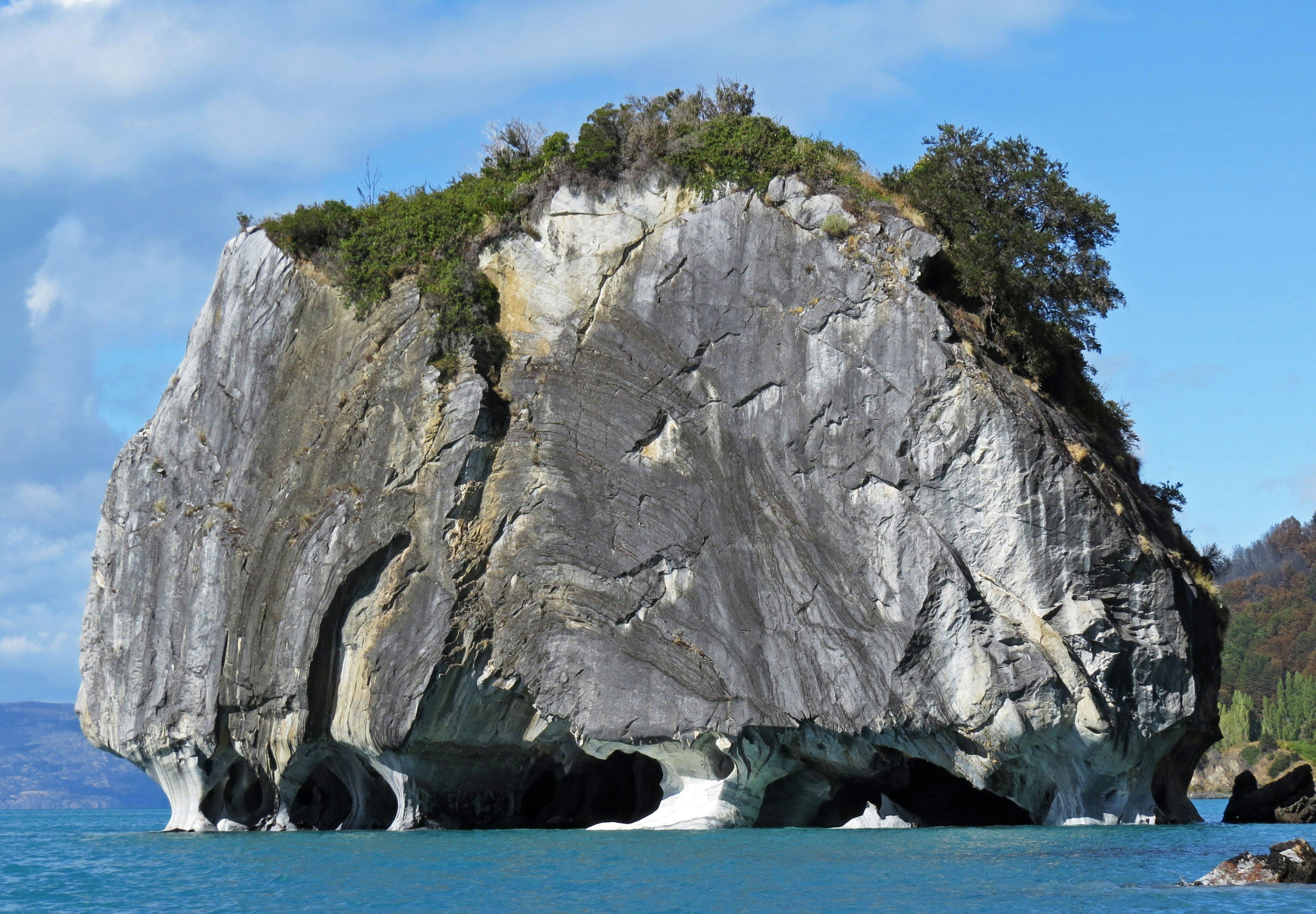 Large rock island in the sea with greenery on top