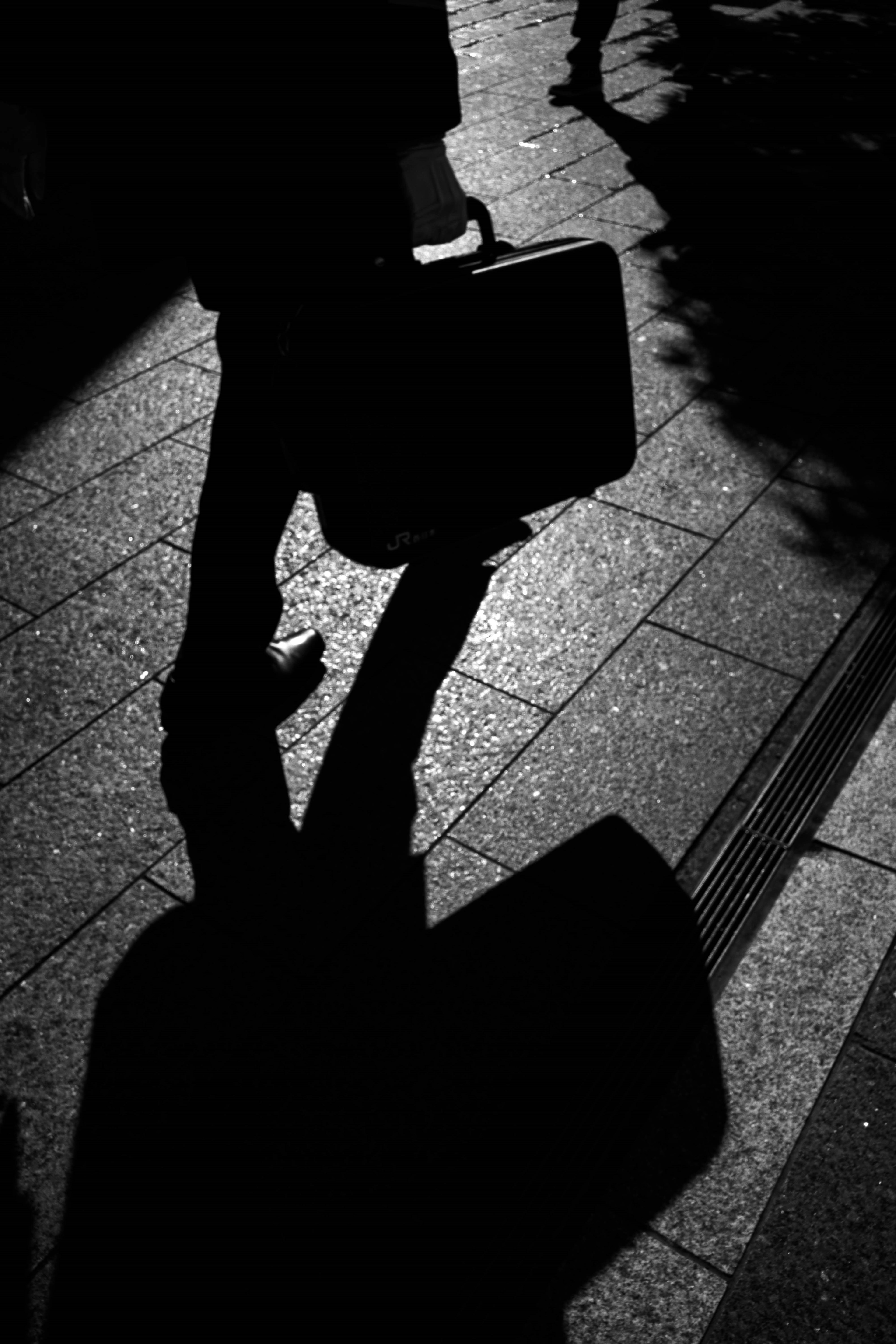 Silhouette of a businessman walking with a briefcase on pavement