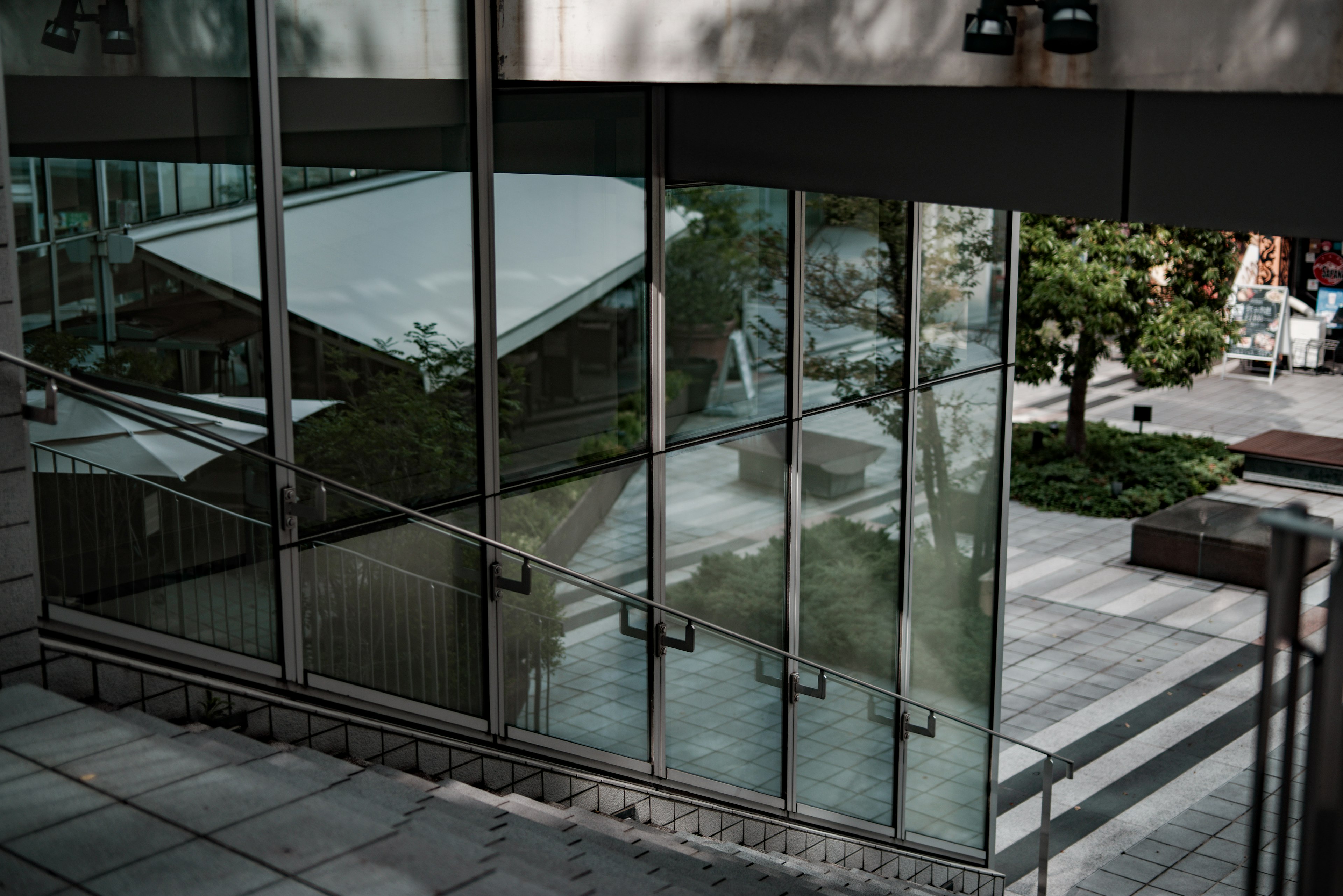 Extérieur d'un bâtiment moderne avec des murs en verre et vue sur le jardin environnant