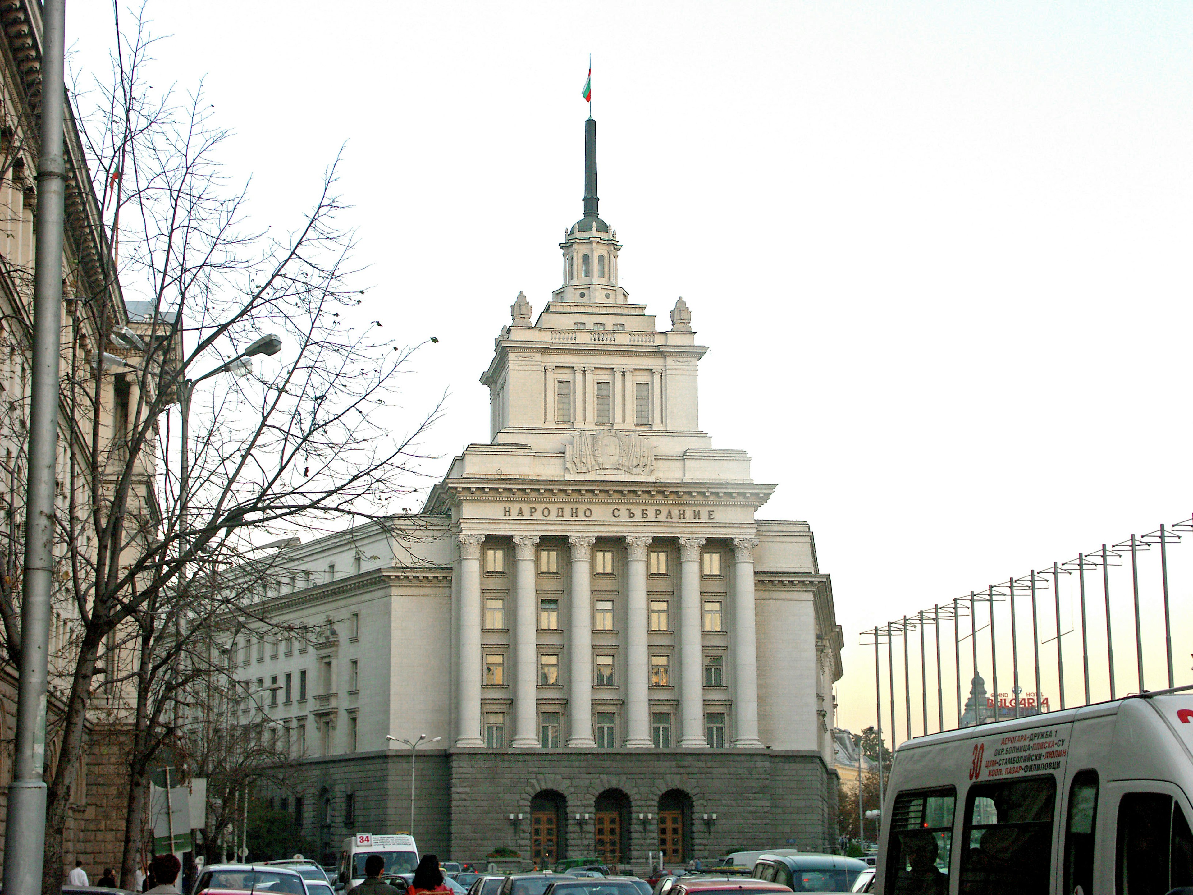 Historic building with a tall spire street and vehicles in front