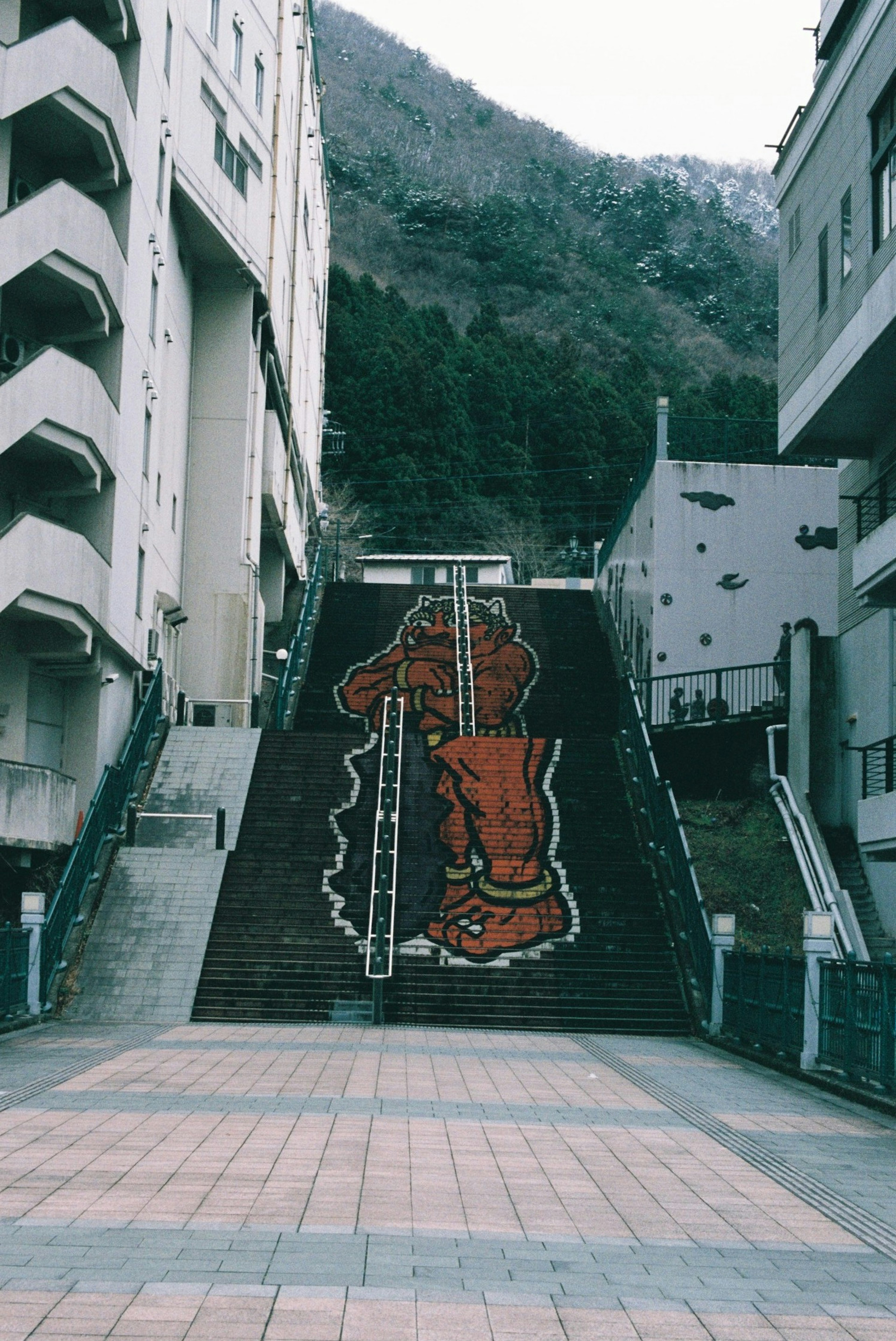 Art de rue représentant un grand pied rouge sur des escaliers avec des bâtiments environnants