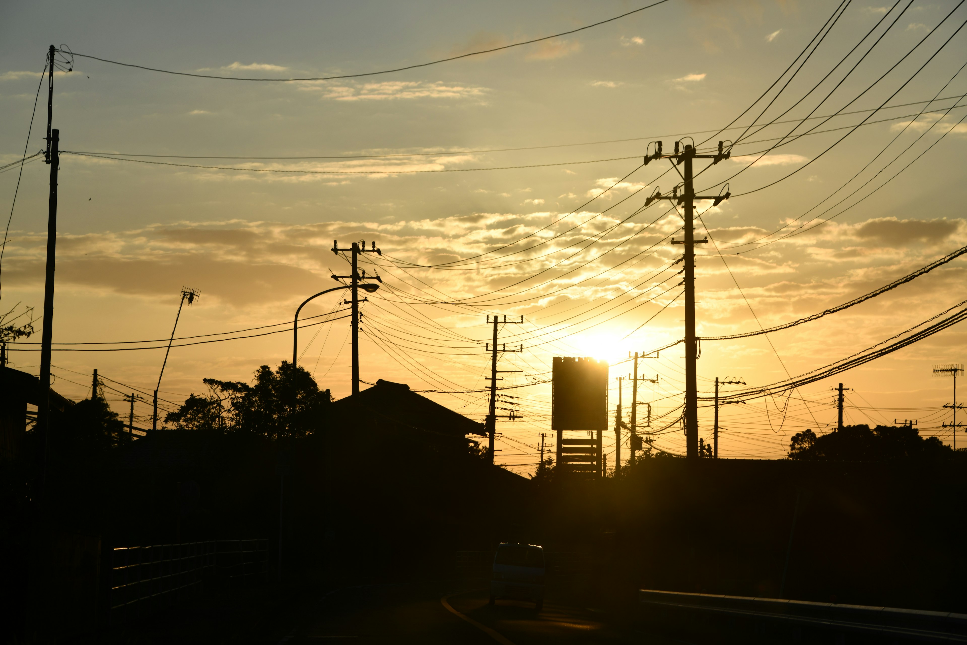 Silhouette von Stromleitungen und Häusern bei Sonnenuntergang