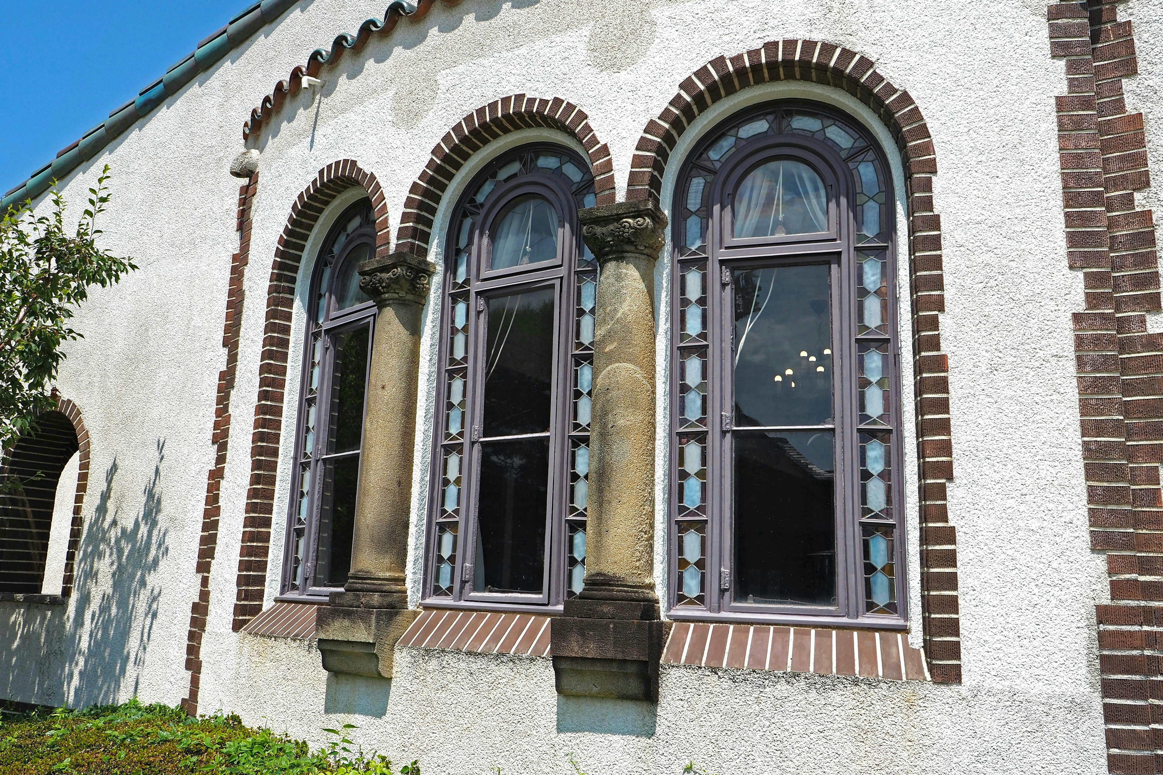 Tres ventanas en arco de un edificio antiguo que muestran detalles arquitectónicos únicos