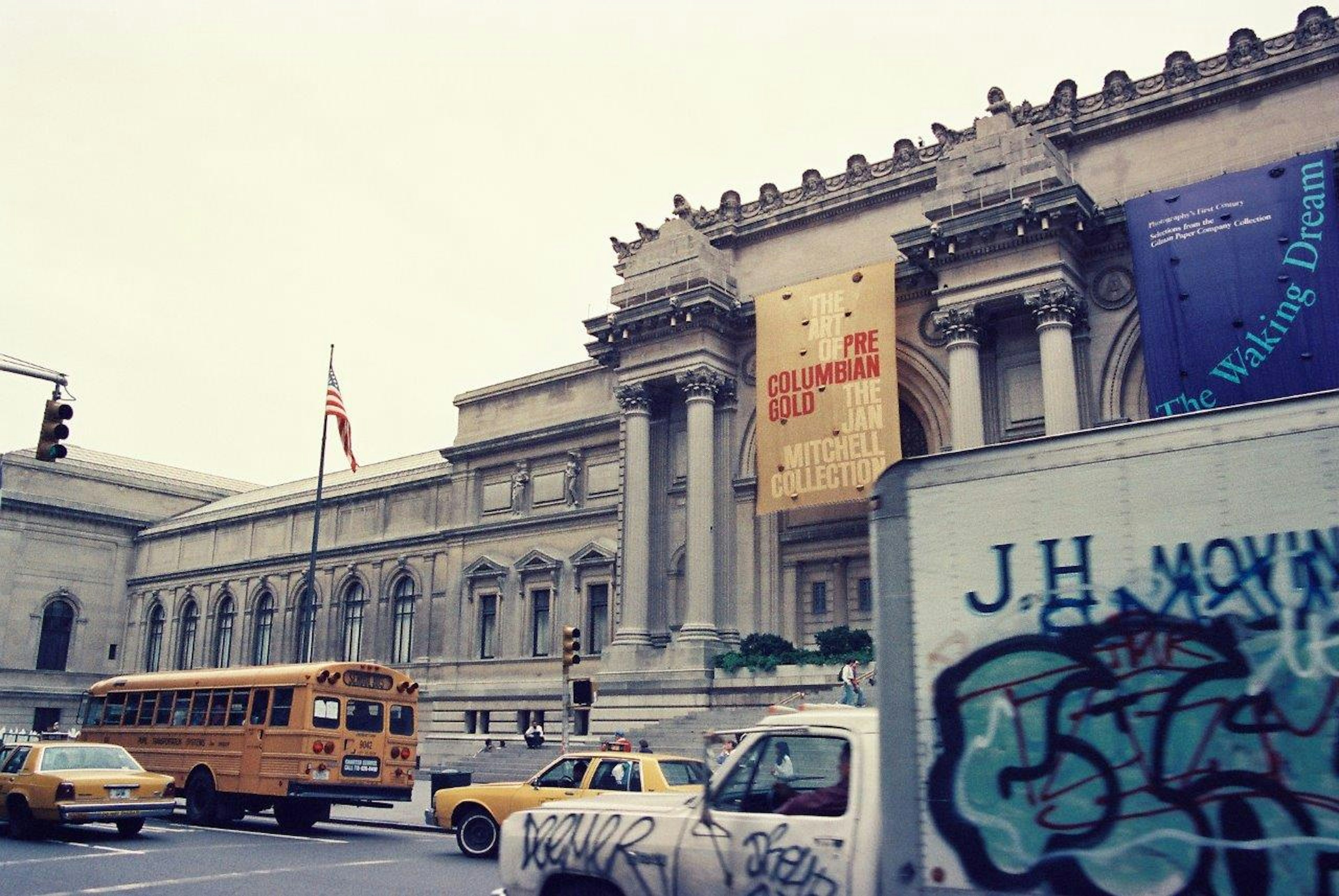 Exterior view of the Metropolitan Museum of Art with yellow taxi and school bus