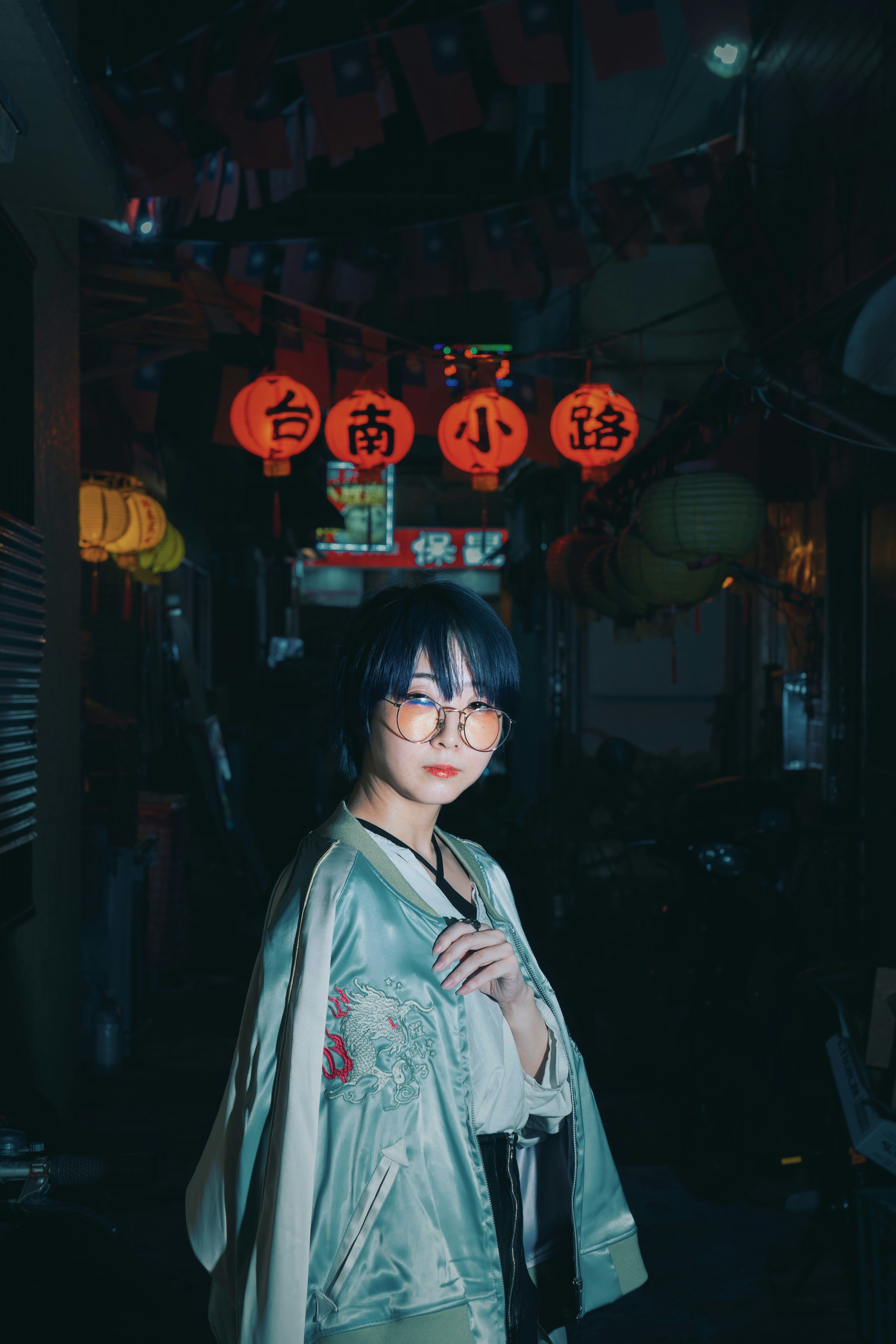 Portrait of a woman posing in dim light wearing a floral patterned outfit with red lanterns in the background