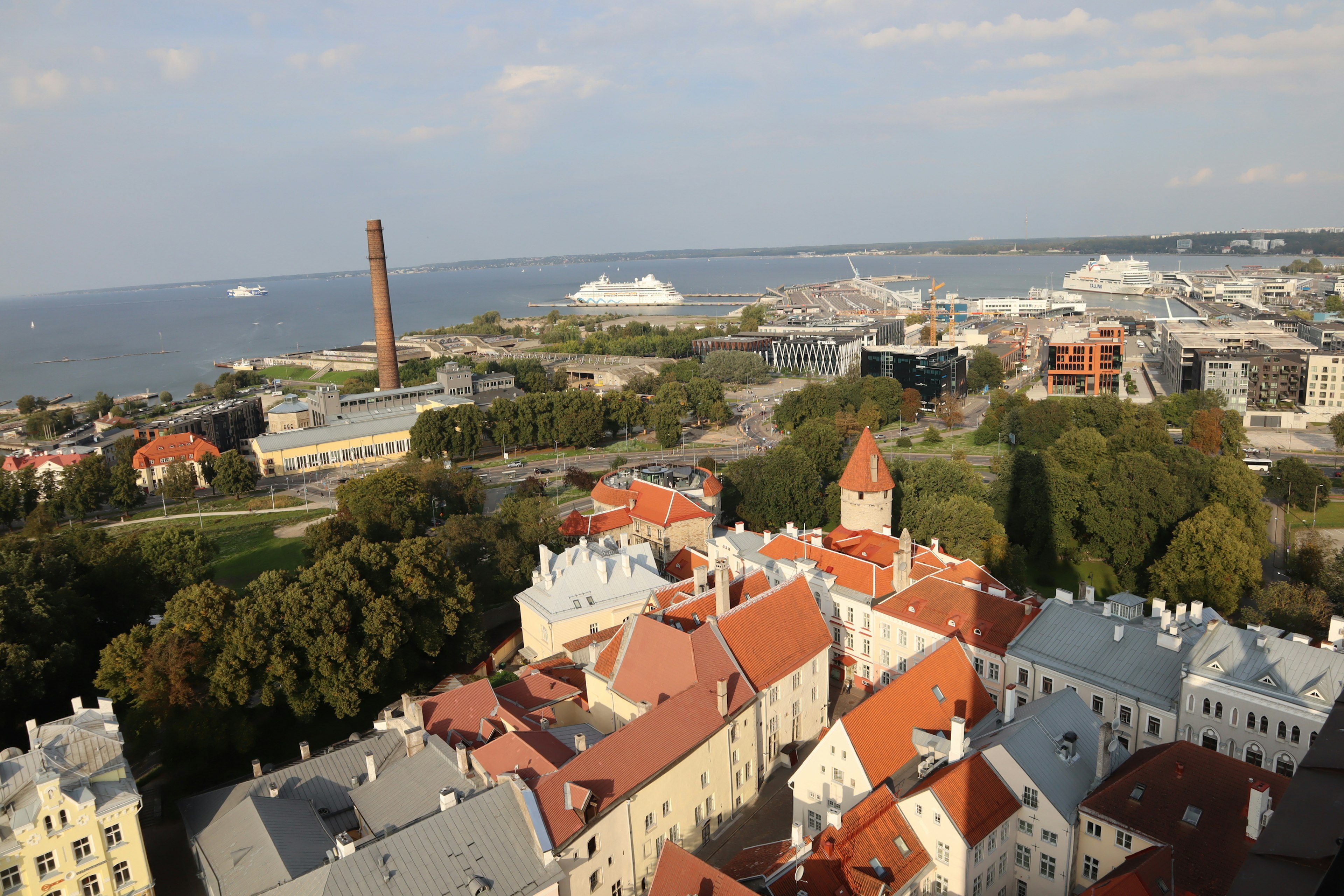 Vista aérea de Tallin Estonia con edificios de techos rojos el mar y estructuras industriales