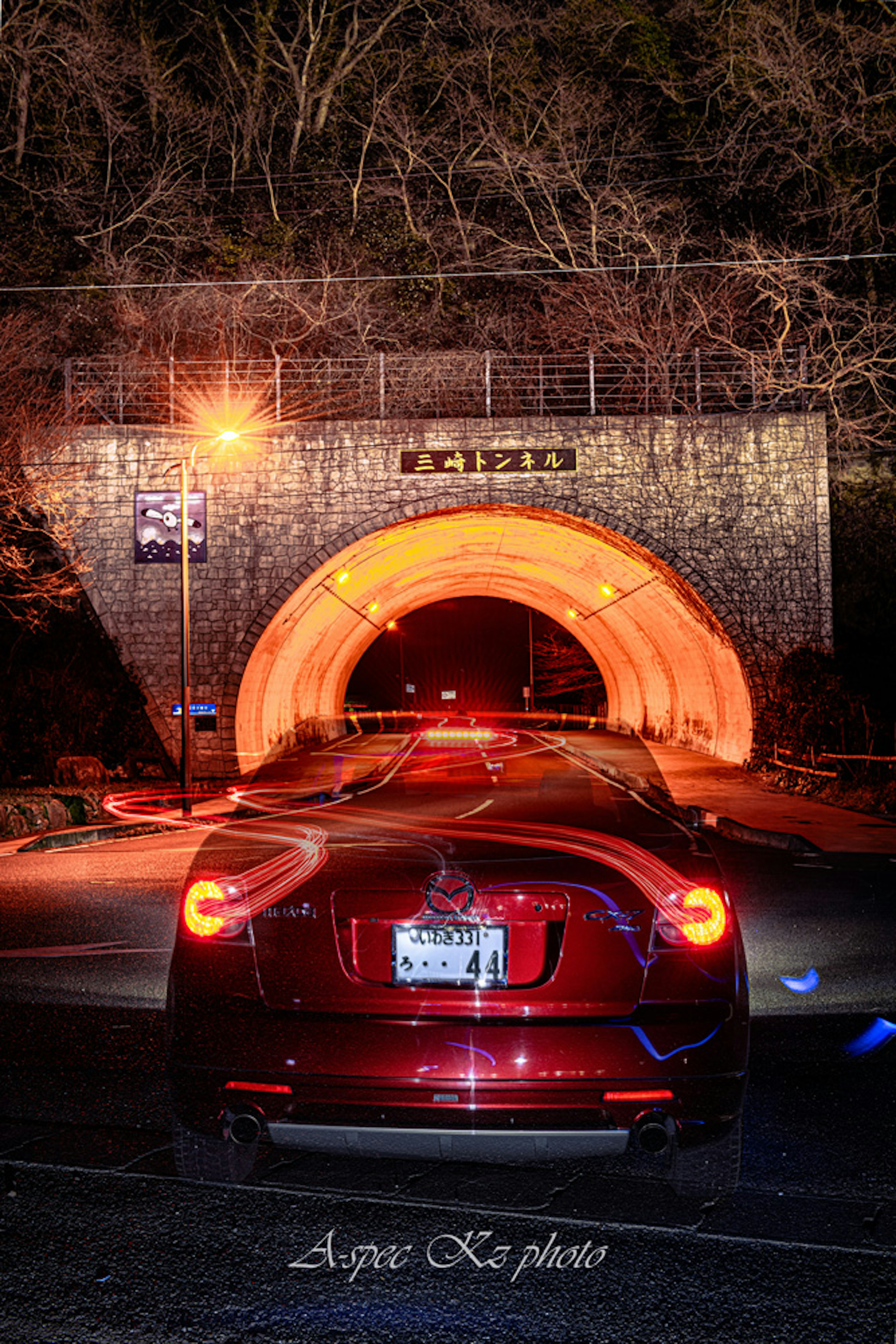 Una foto di un'auto rossa parcheggiata all'ingresso di un tunnel con una bella illuminazione notturna