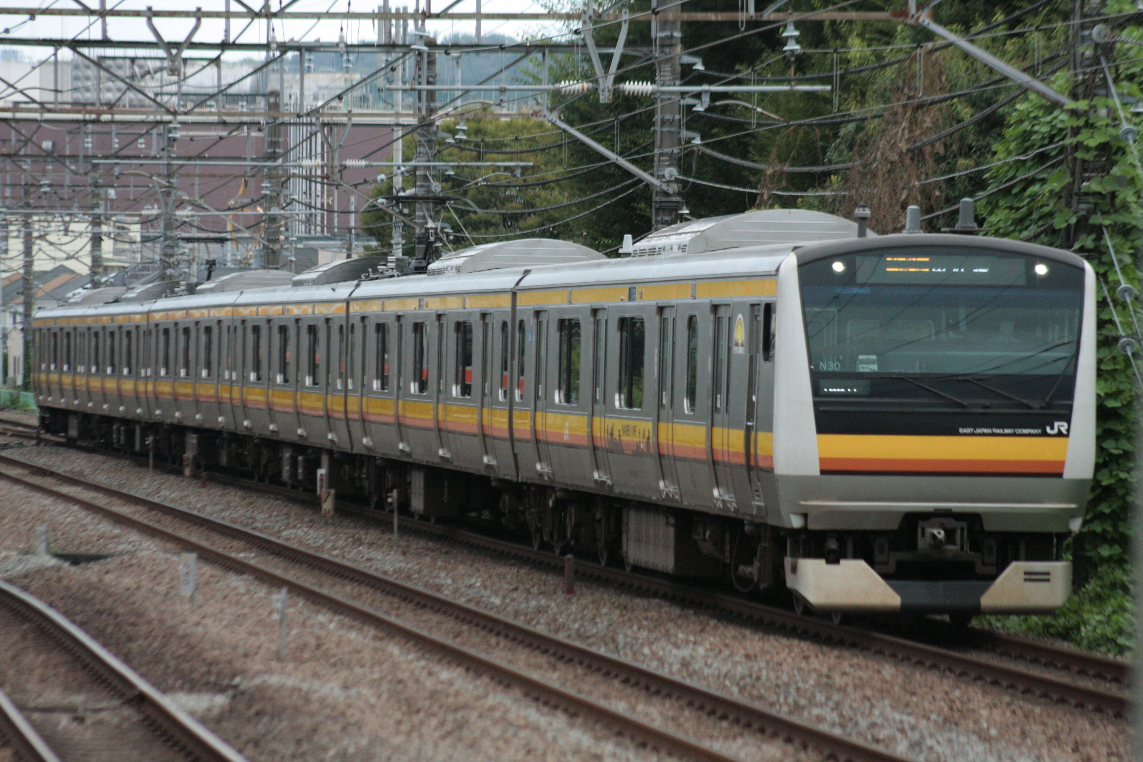 Train with yellow and gray stripes parked on tracks