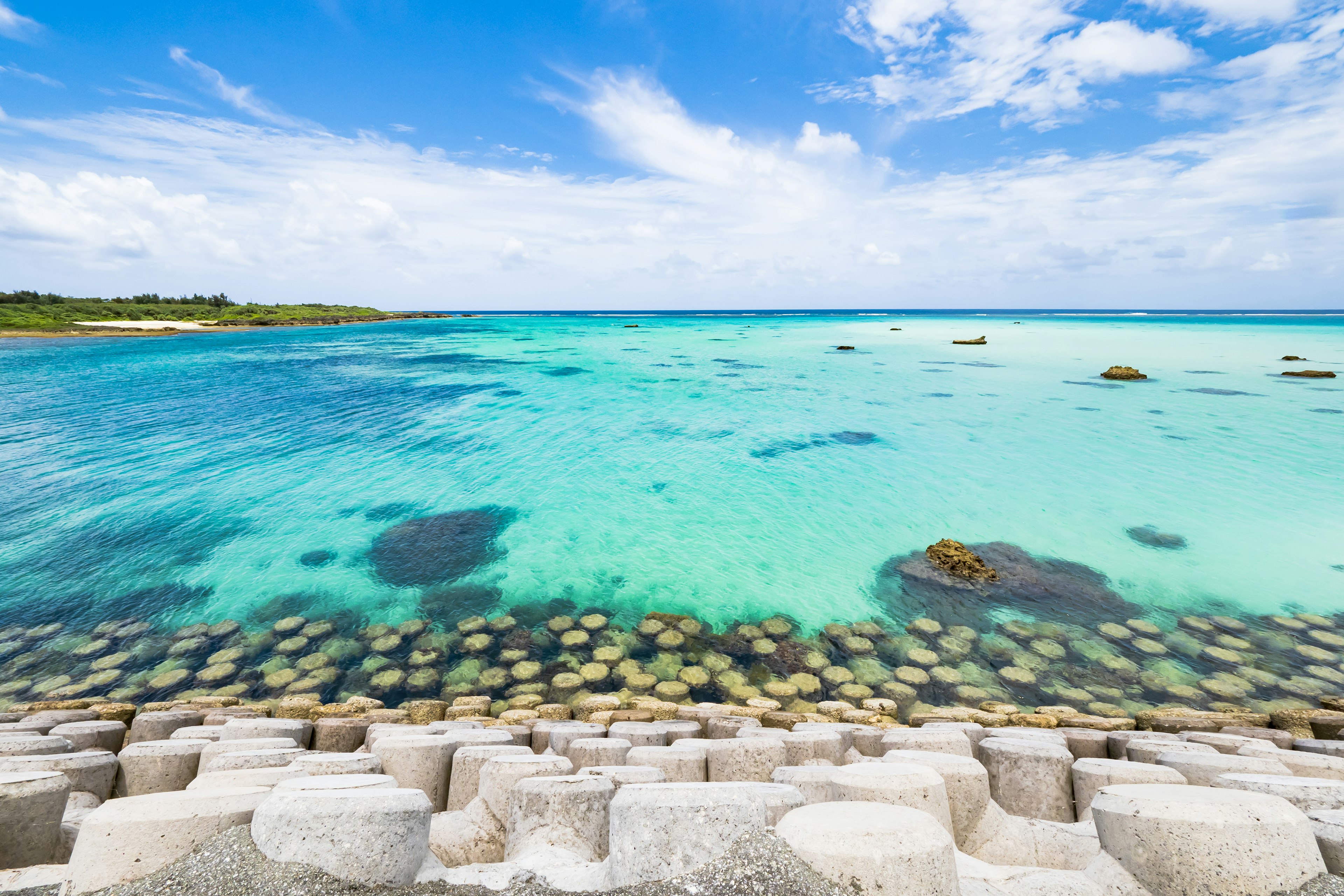 美丽的海岸风景，蓝色海洋和白色云朵，石头堤防可见