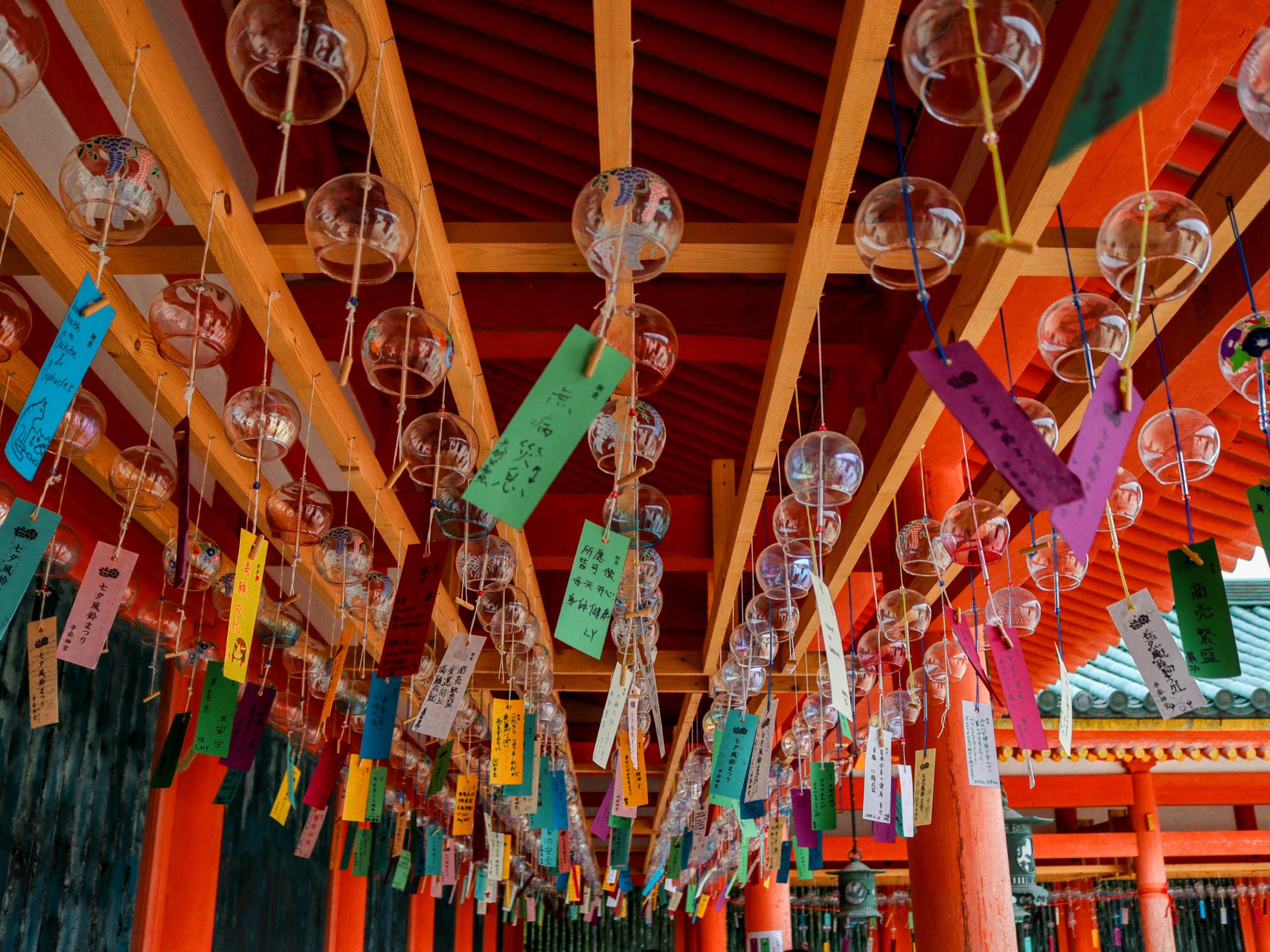 Colorful wind chimes hanging under a shrine roof