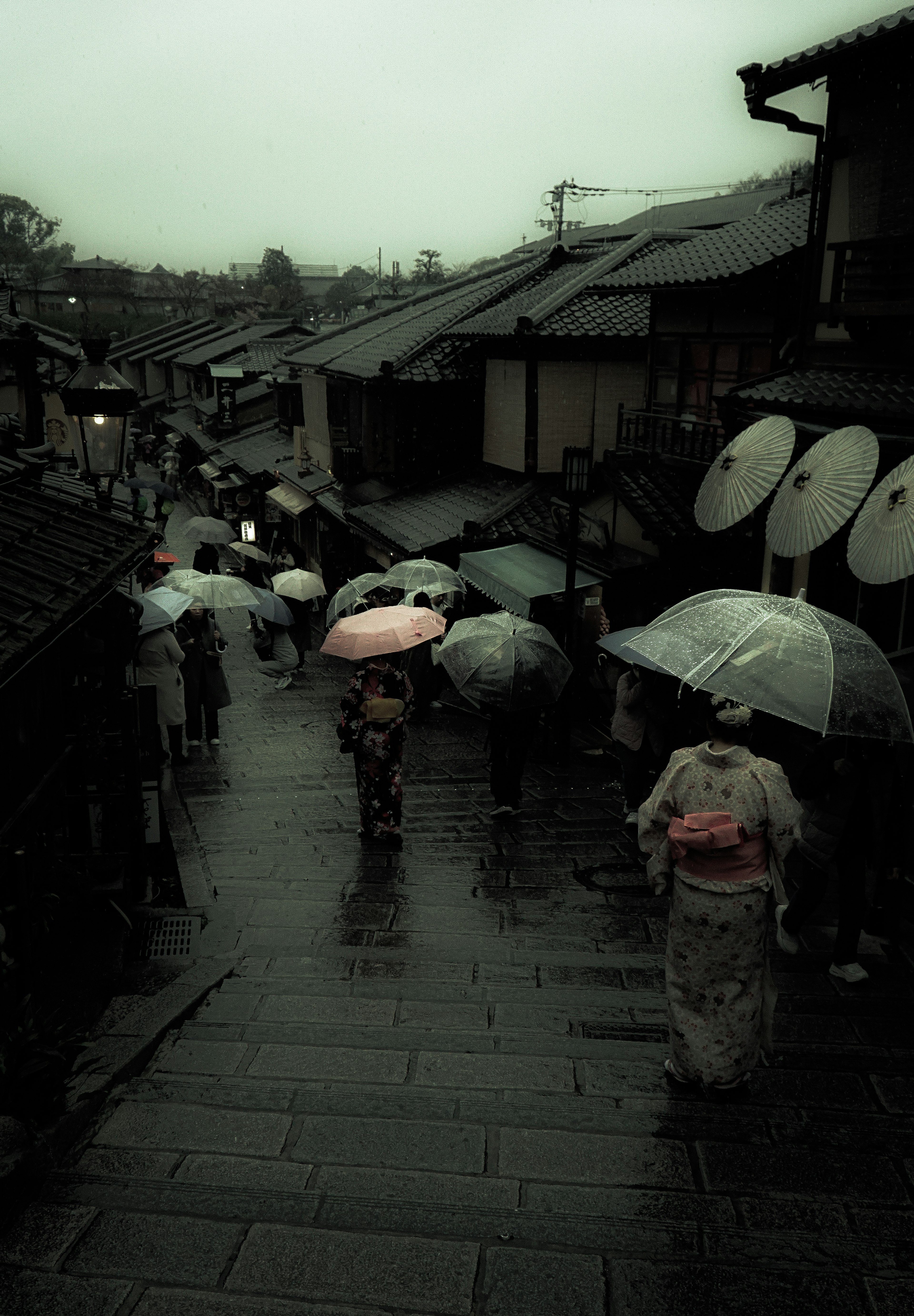 People walking under umbrellas in a historic street during rain