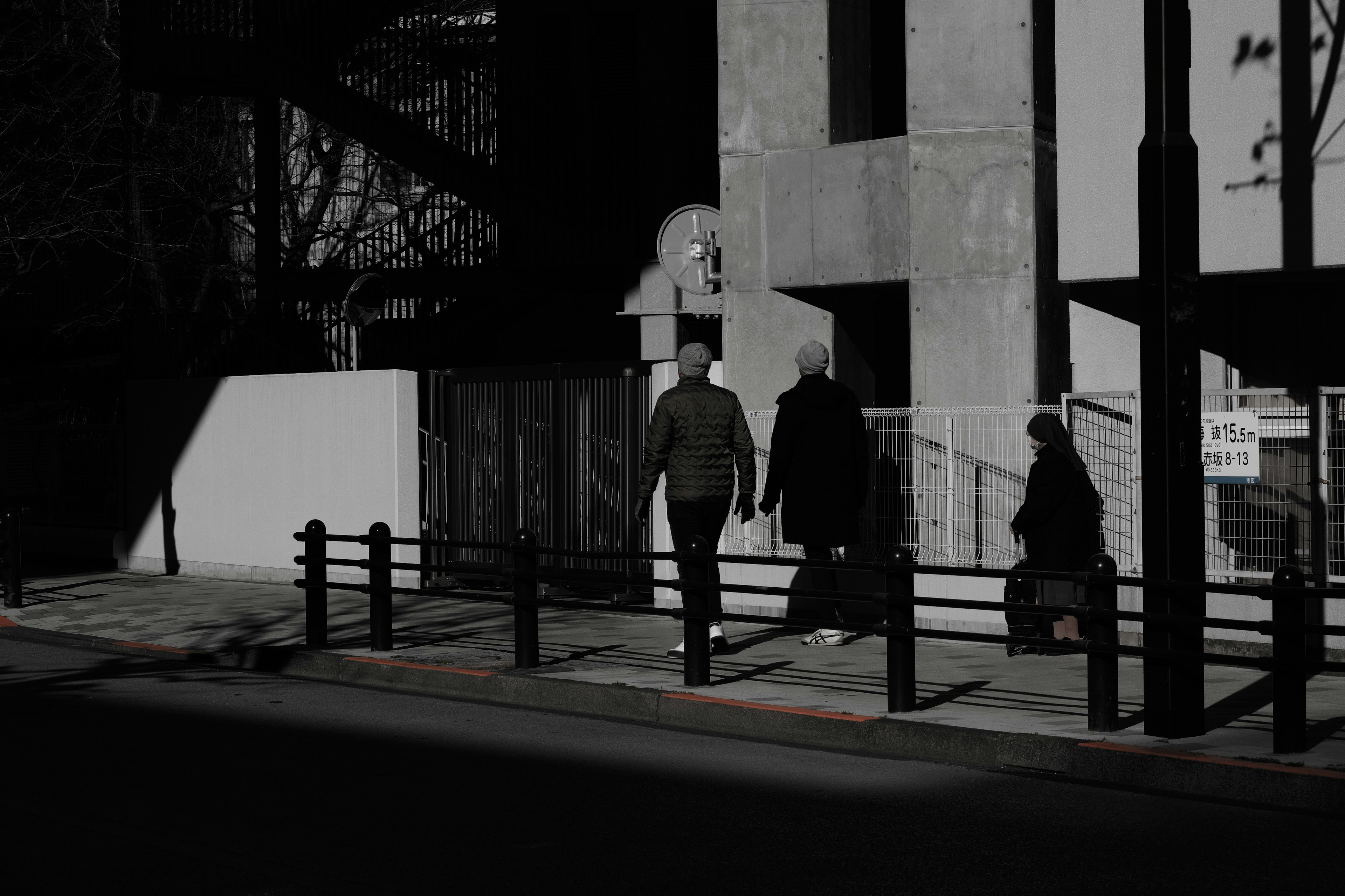 Silhouettes of people walking on a dark street with a building in the background