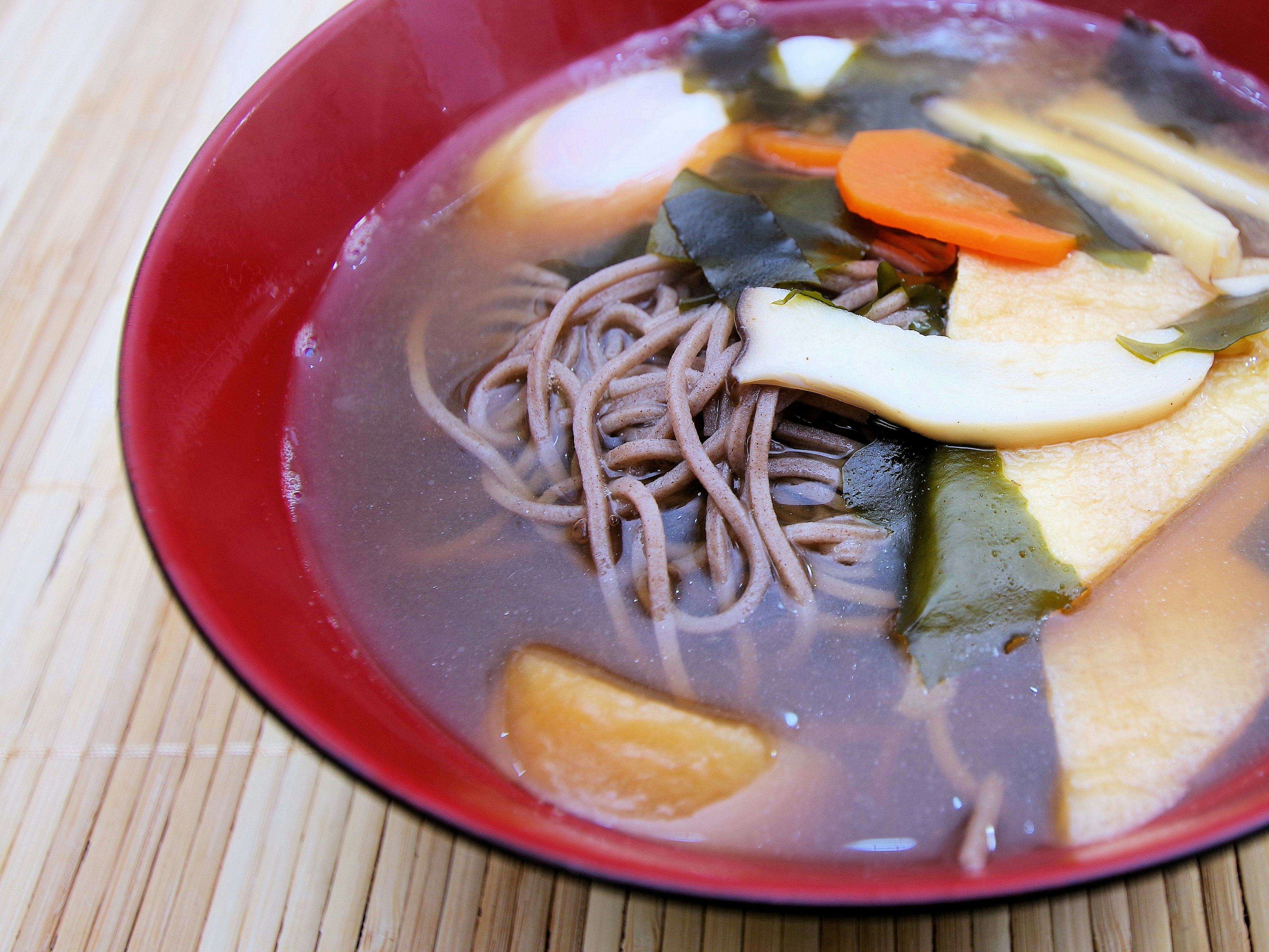 A bowl of soba noodles in broth with vegetables