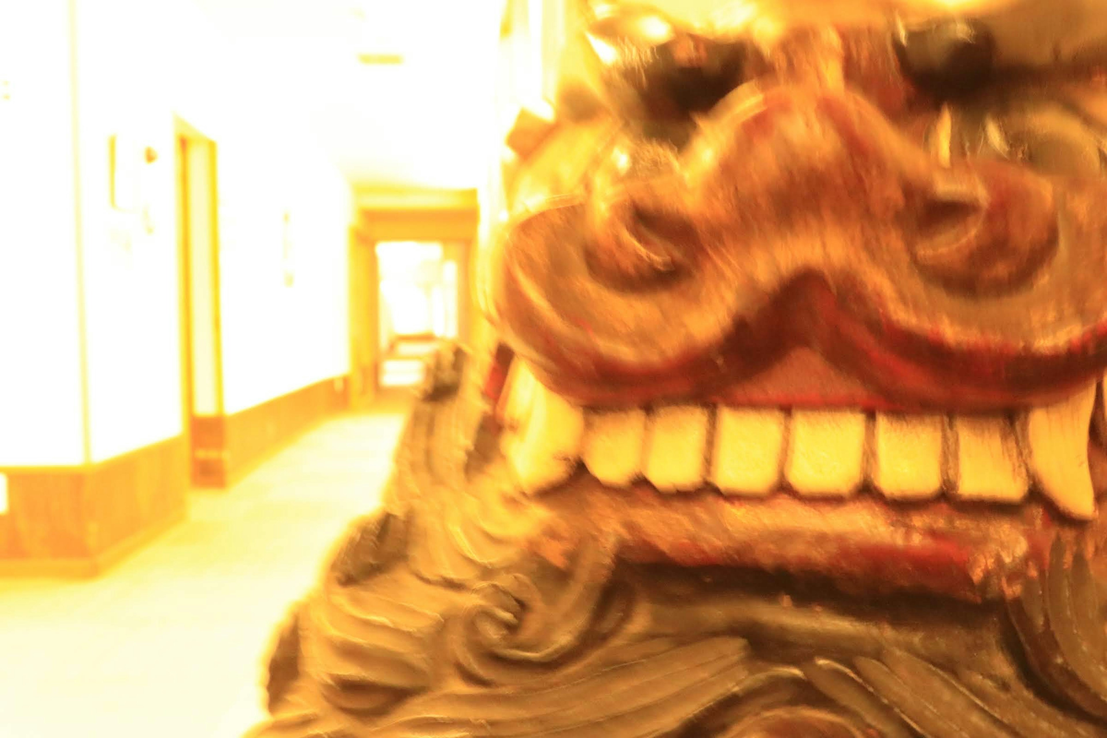 Close-up of a wooden sculpture displaying a fearsome face with large teeth