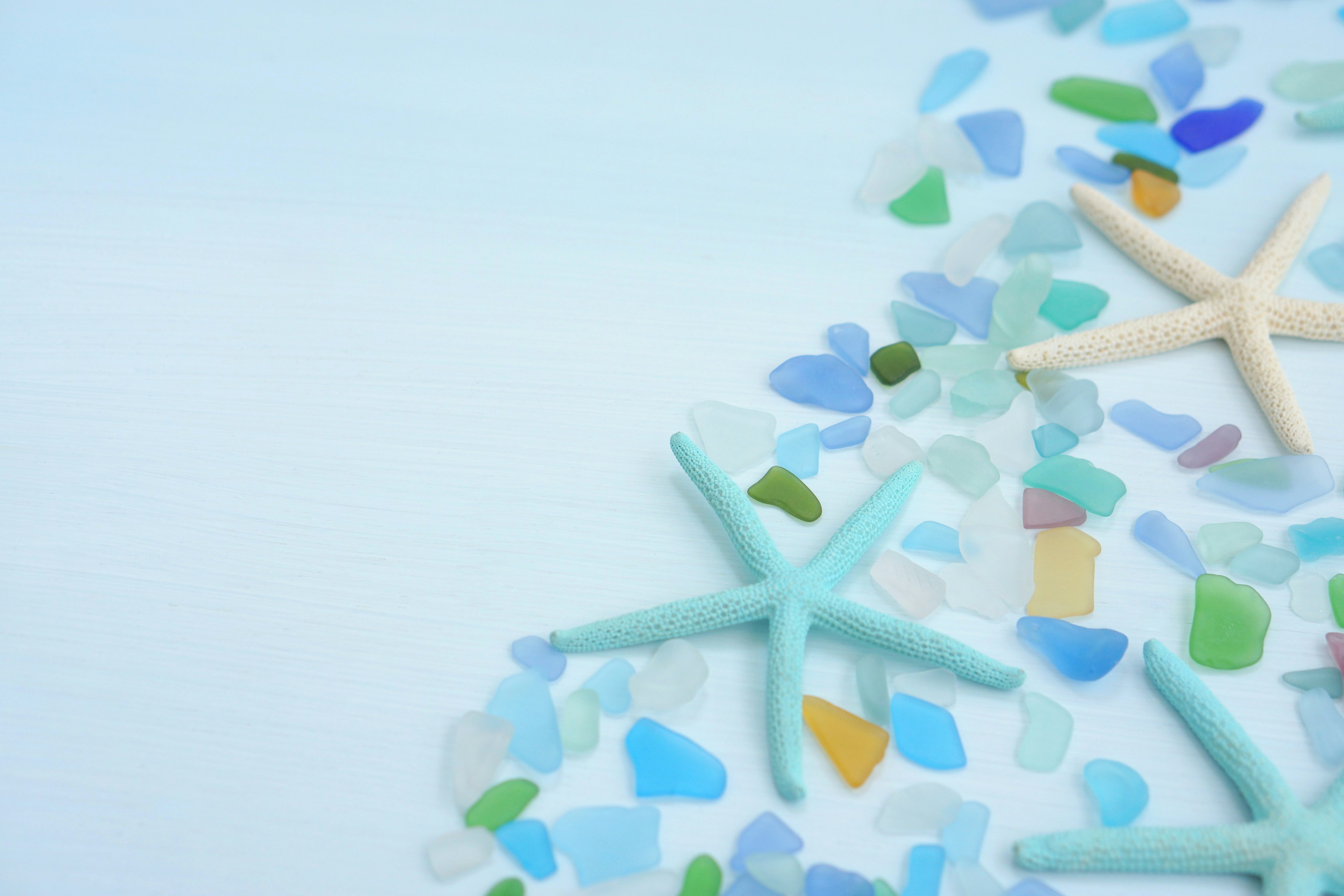 Starfish and colorful sea glass scattered on a blue background