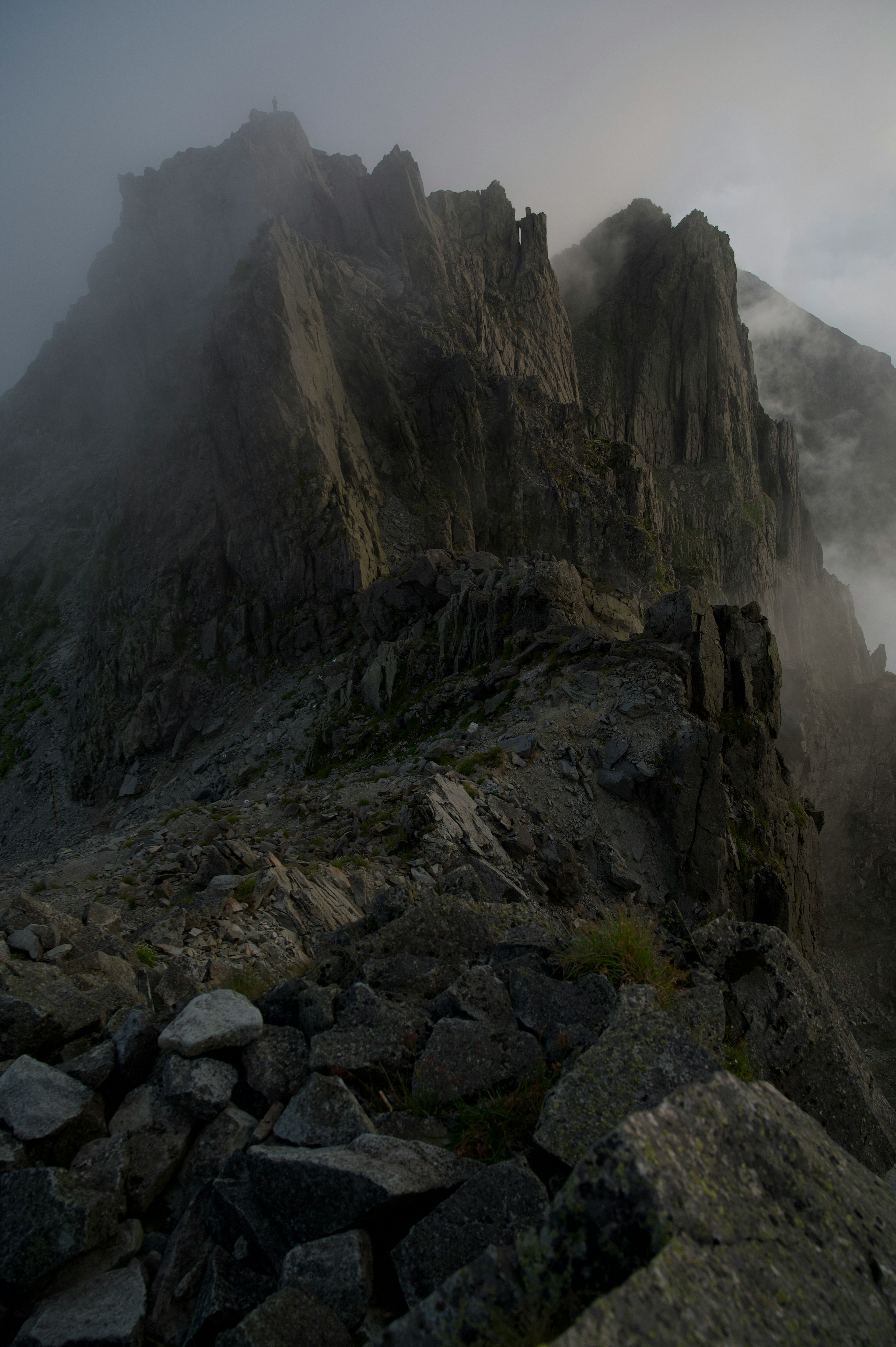 Vista nebbiosa di un picco montuoso scosceso e terreno roccioso