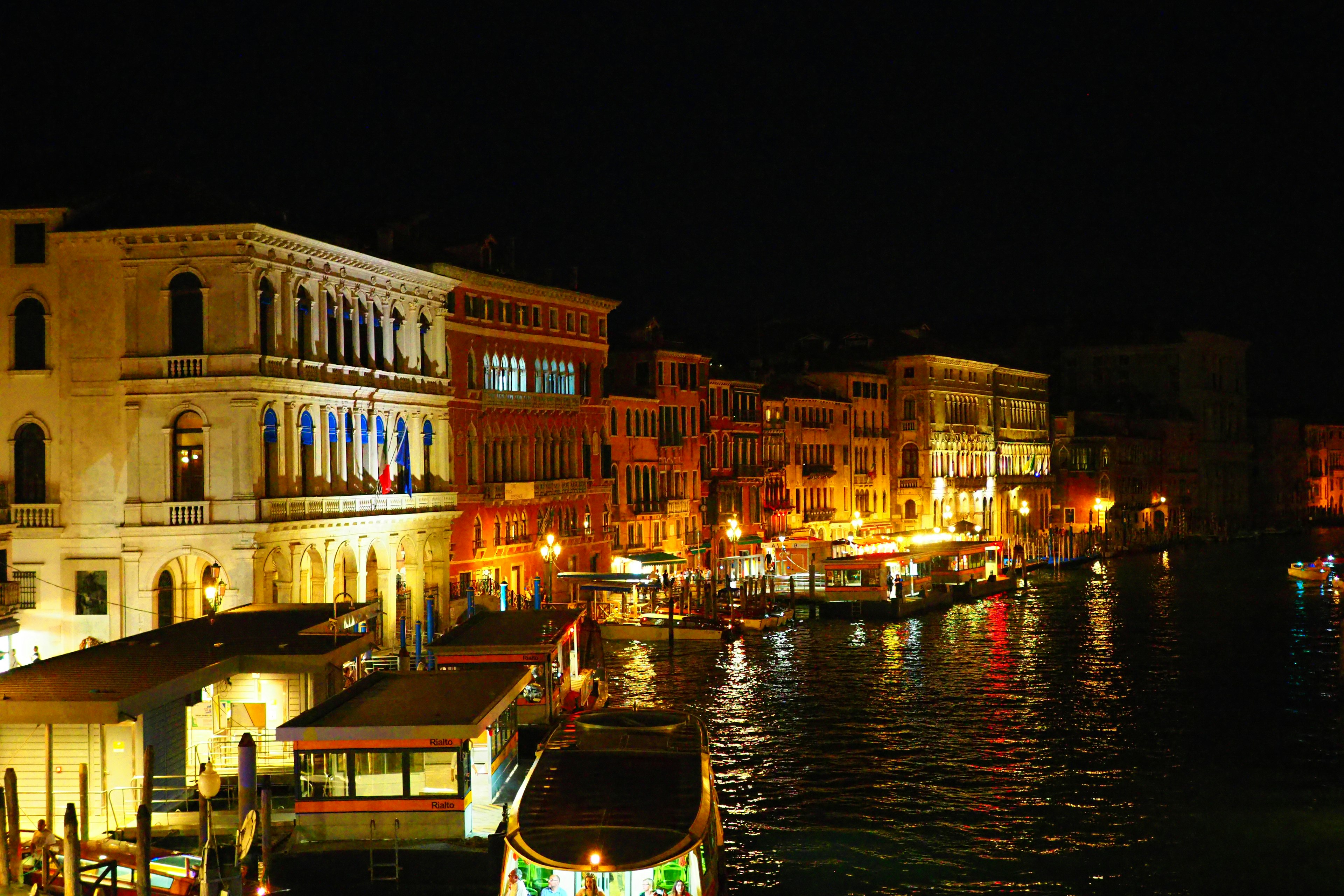 Pemandangan malam Venesia dengan bangunan yang diterangi dan perahu di kanal