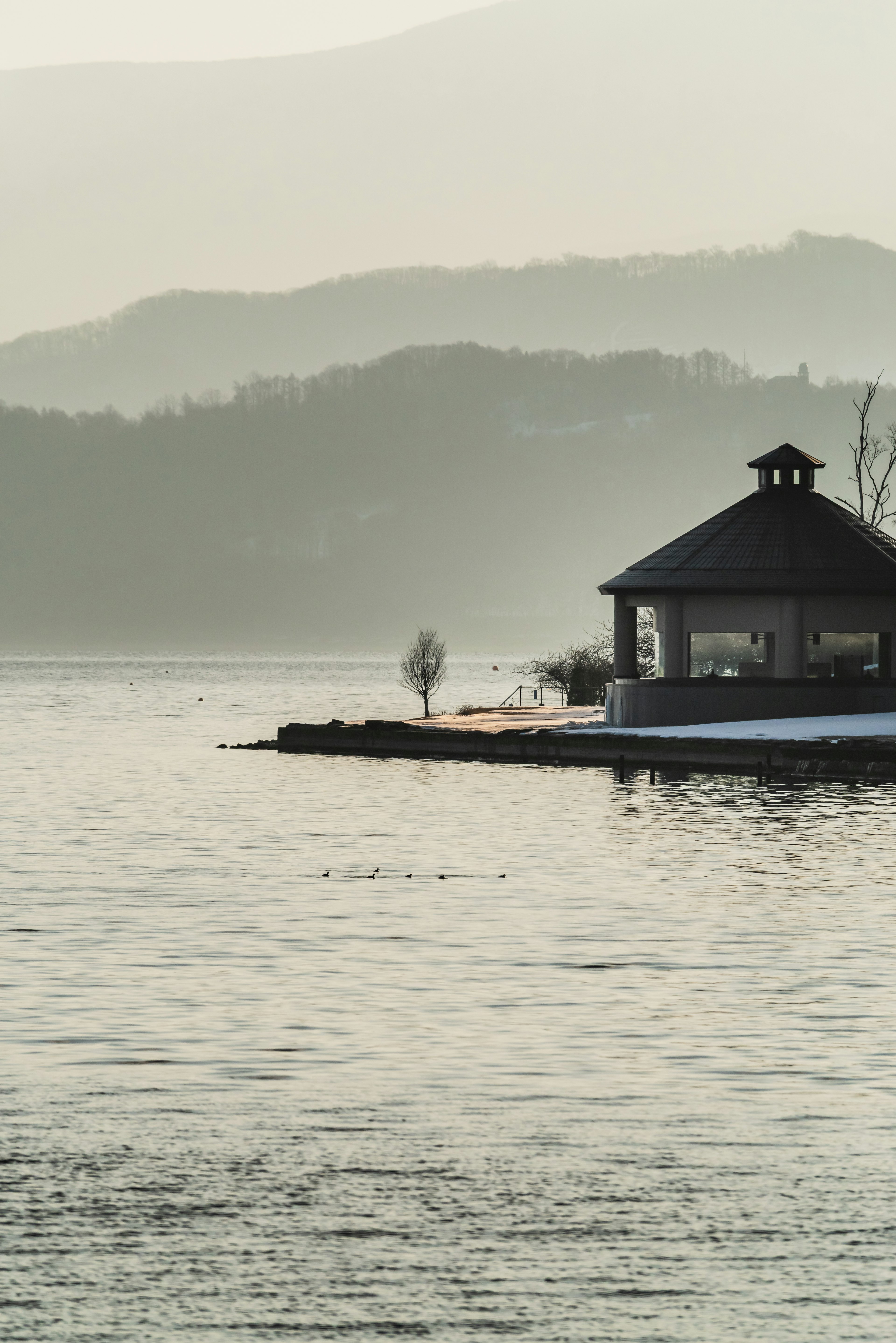 Ein ruhiger Pavillon am See mit Bergen im Hintergrund