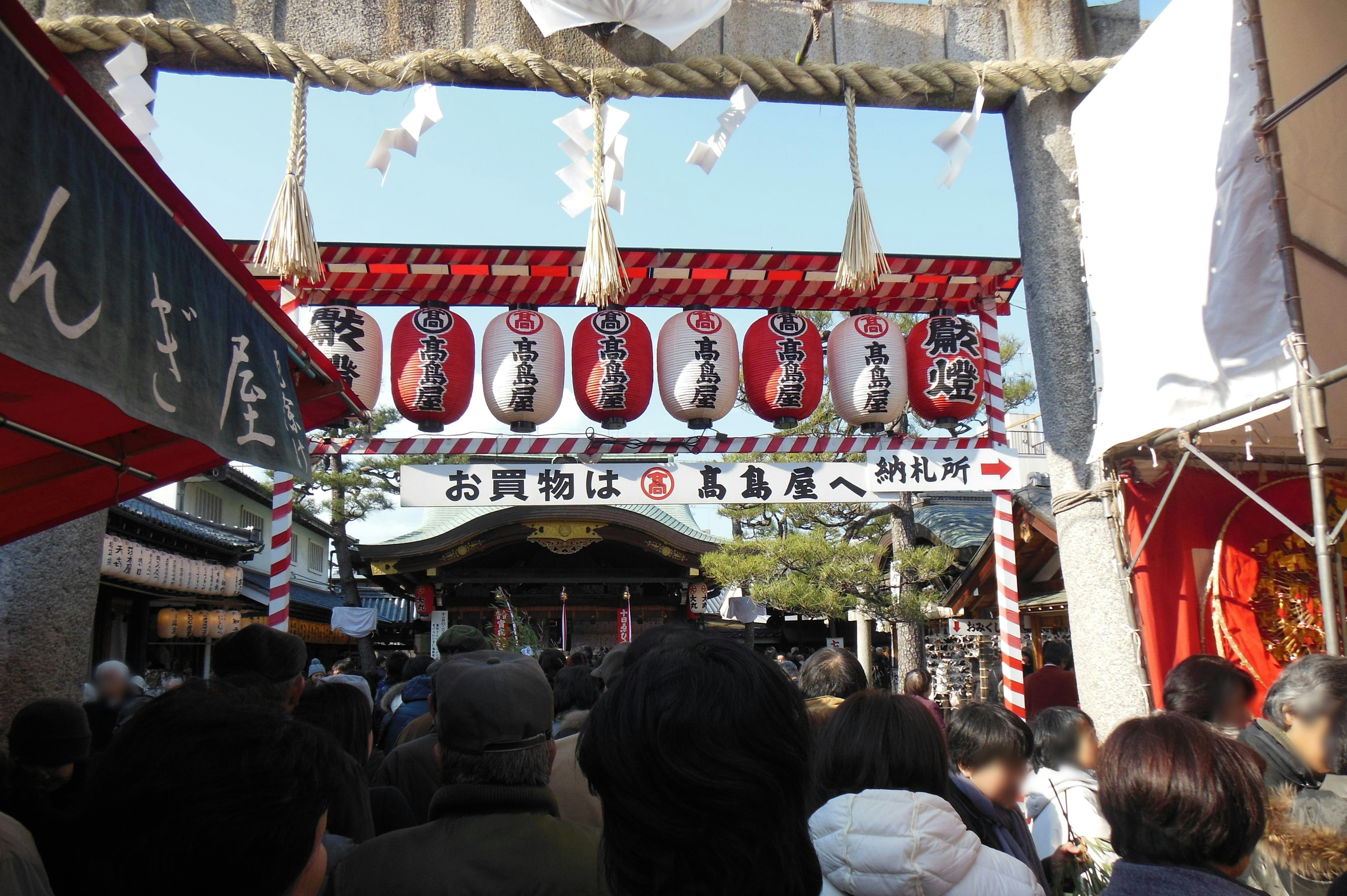 Crowd gathered at a lively shrine entrance adorned with lanterns