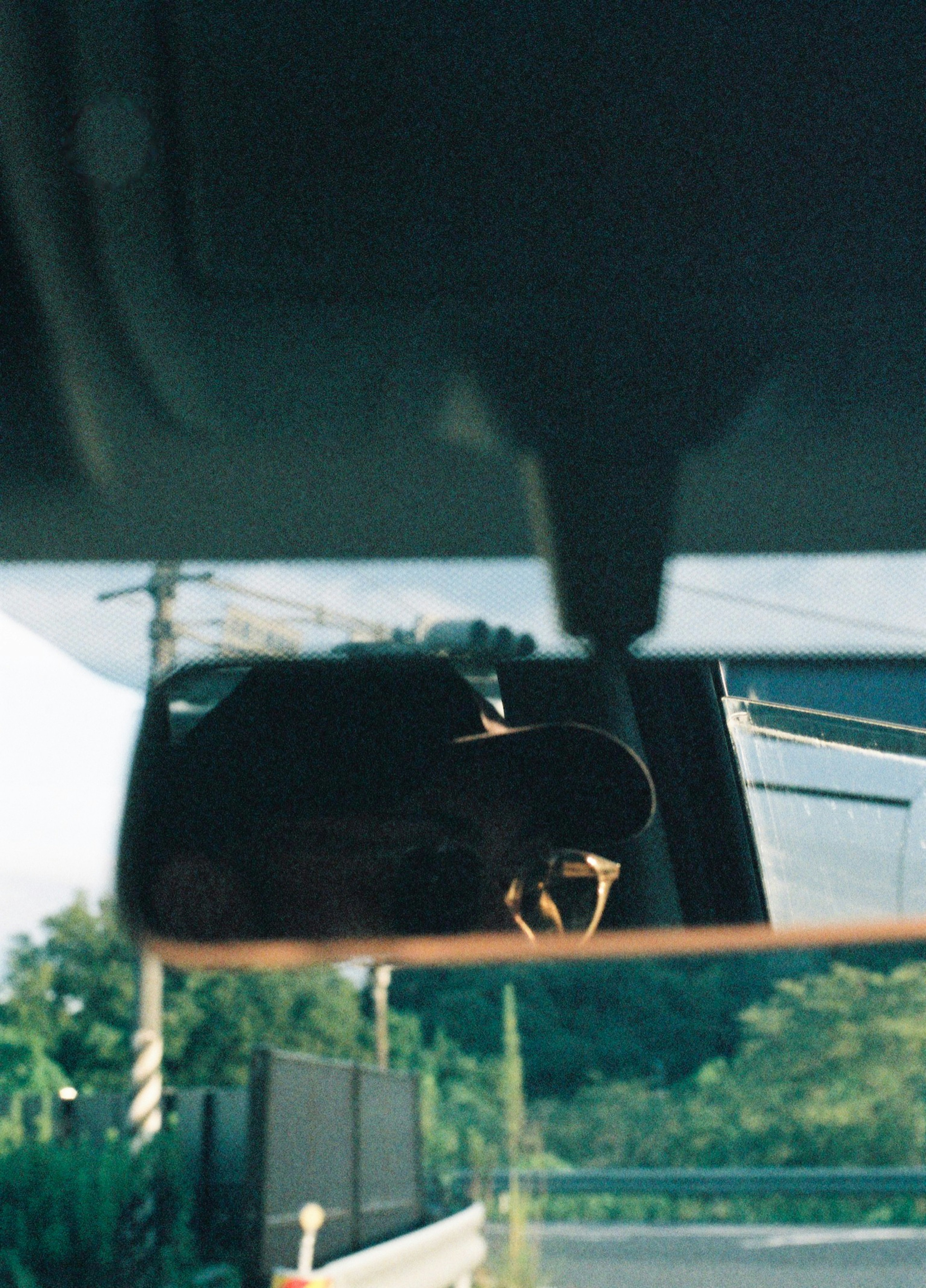 Reflection of a person in a car mirror with surrounding scenery