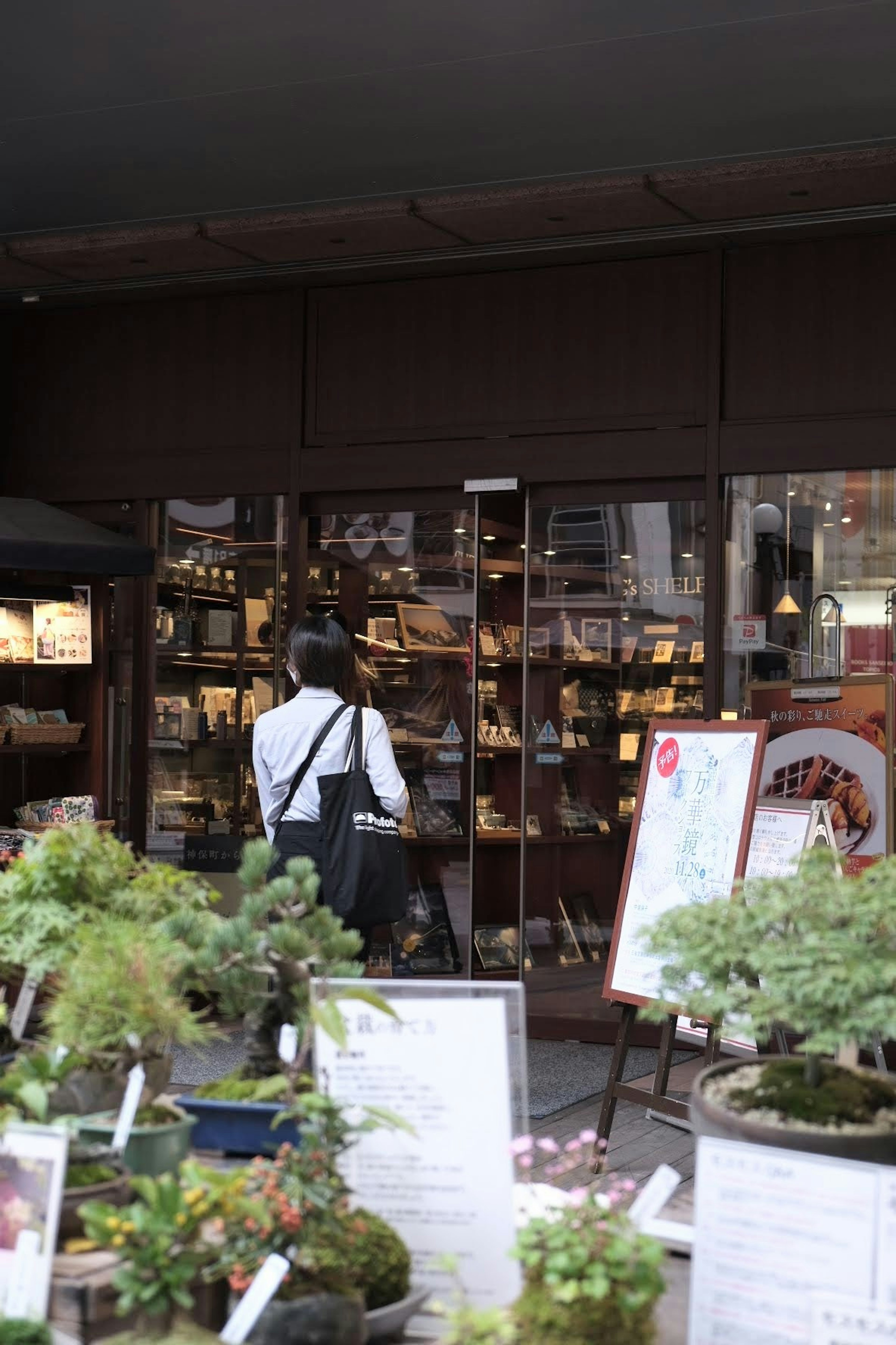 人が入店しようとしている店舗の外観 緑の植物が手前に配置されている