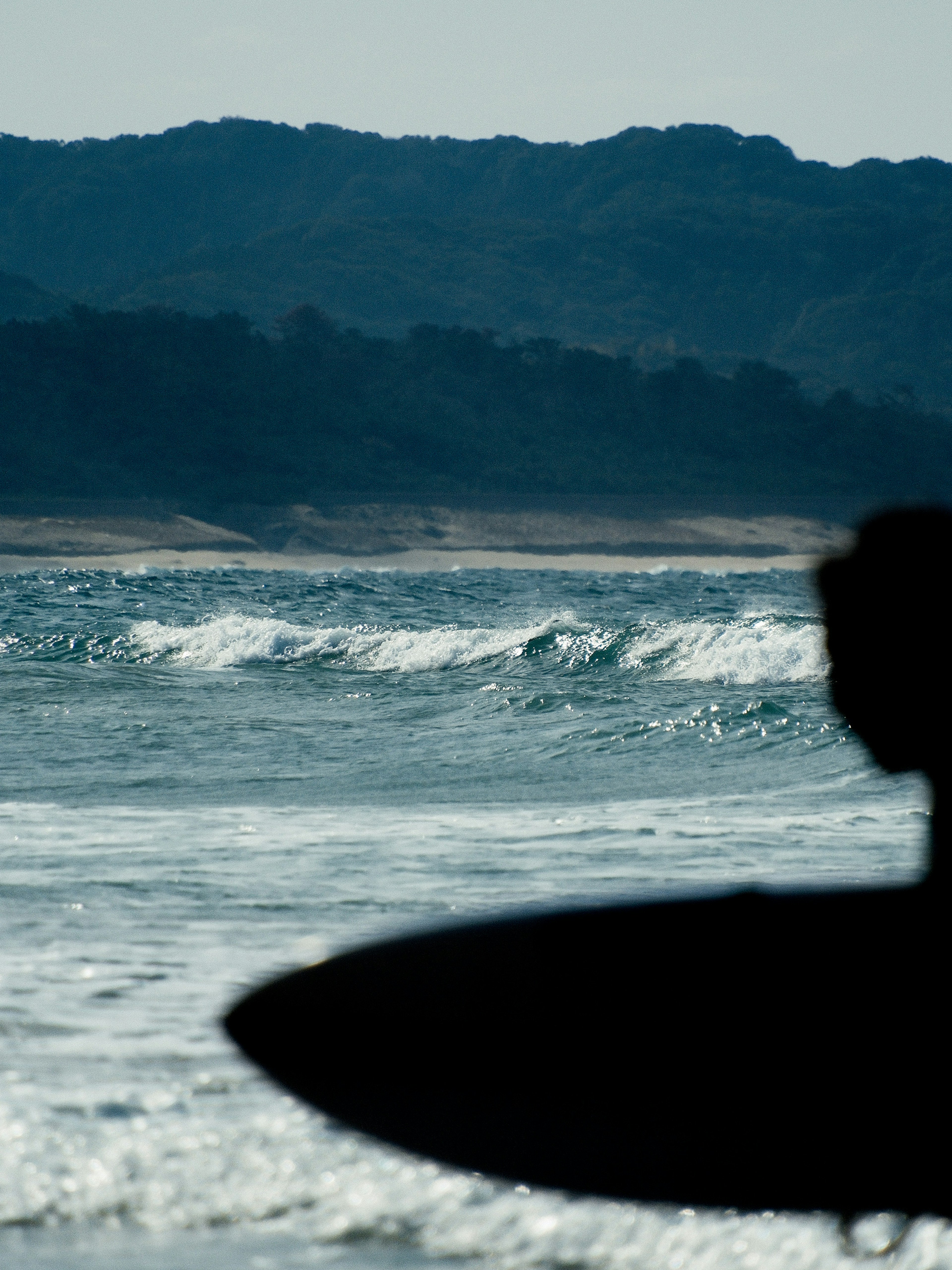 Silhouette eines Surfers mit einem Surfbrett und Wellen im Ozean