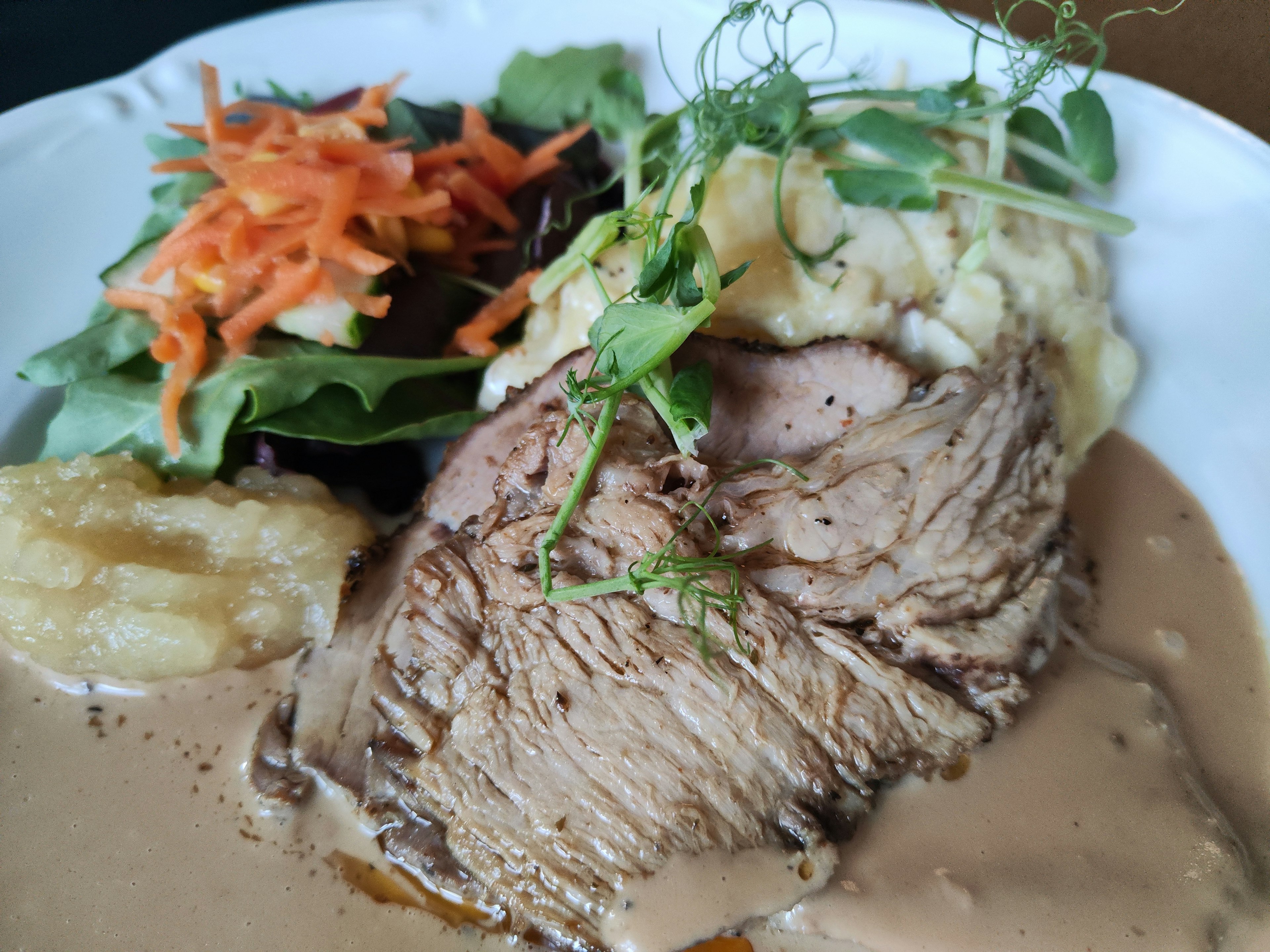 Leckeres Rinderbraten mit cremiger Sauce und Kartoffelbrei serviert mit Salat und geraspelten Karotten