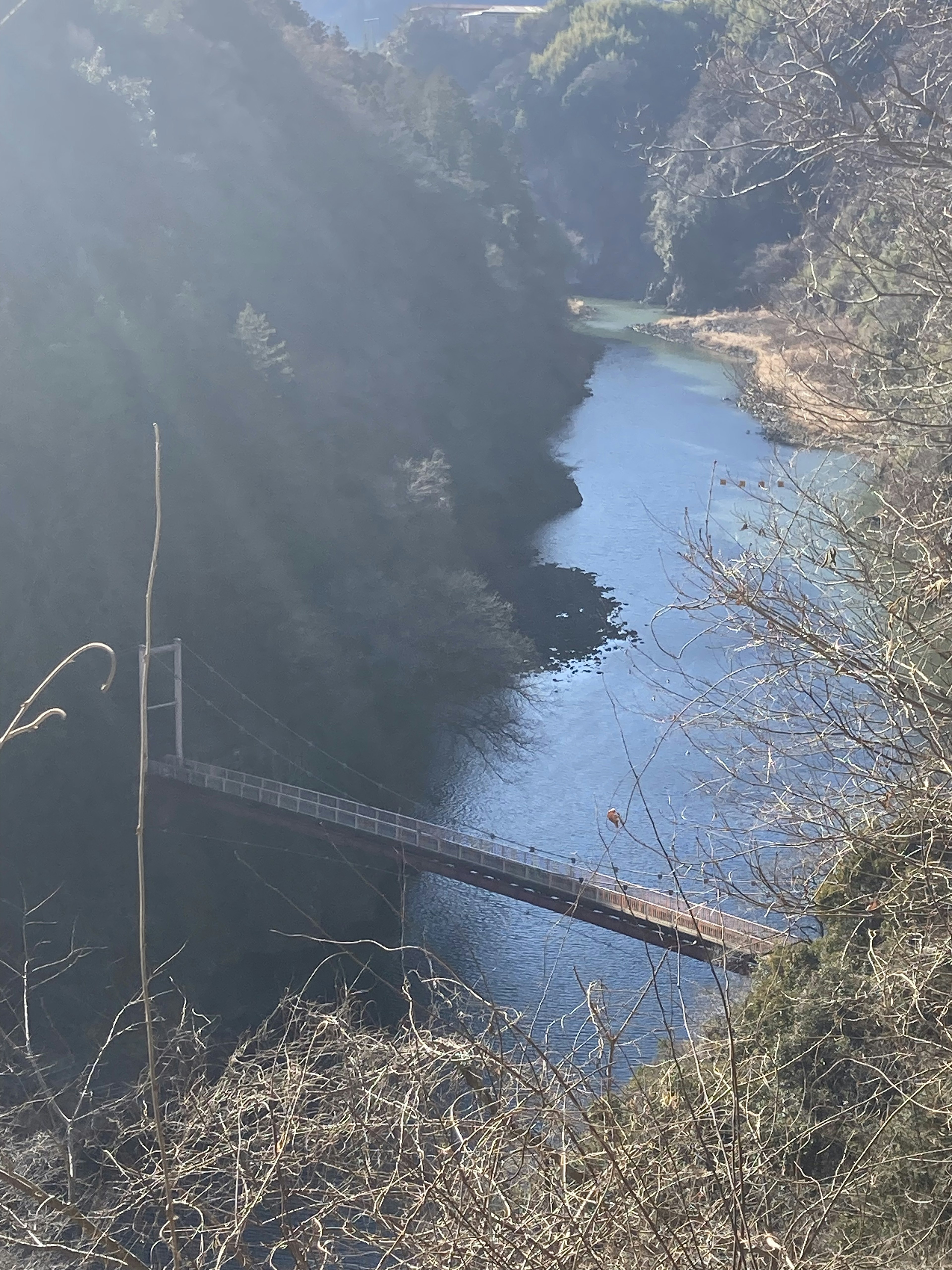 青い川と吊り橋の風景、周囲は緑の山々と自然