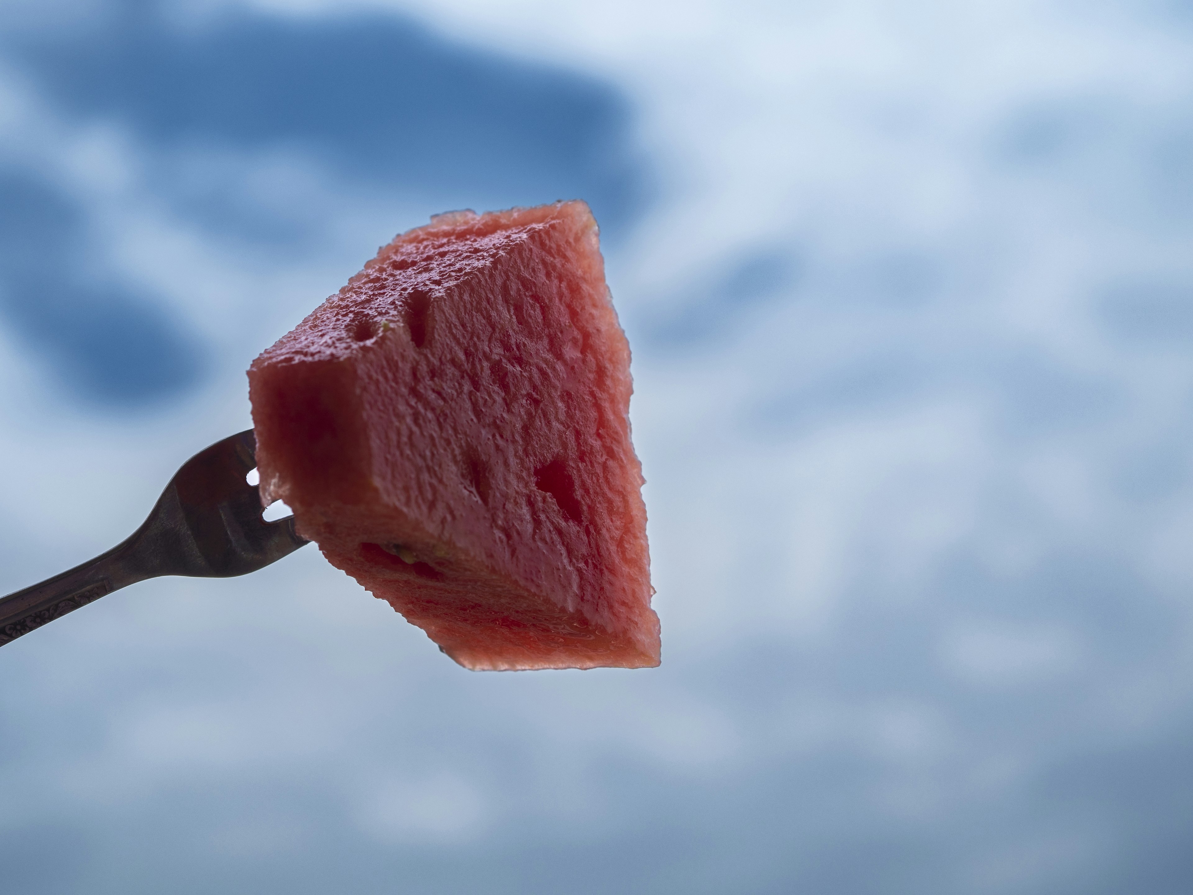 Ein Stück Wassermelone auf einer Gabel vor einem blauen Himmel