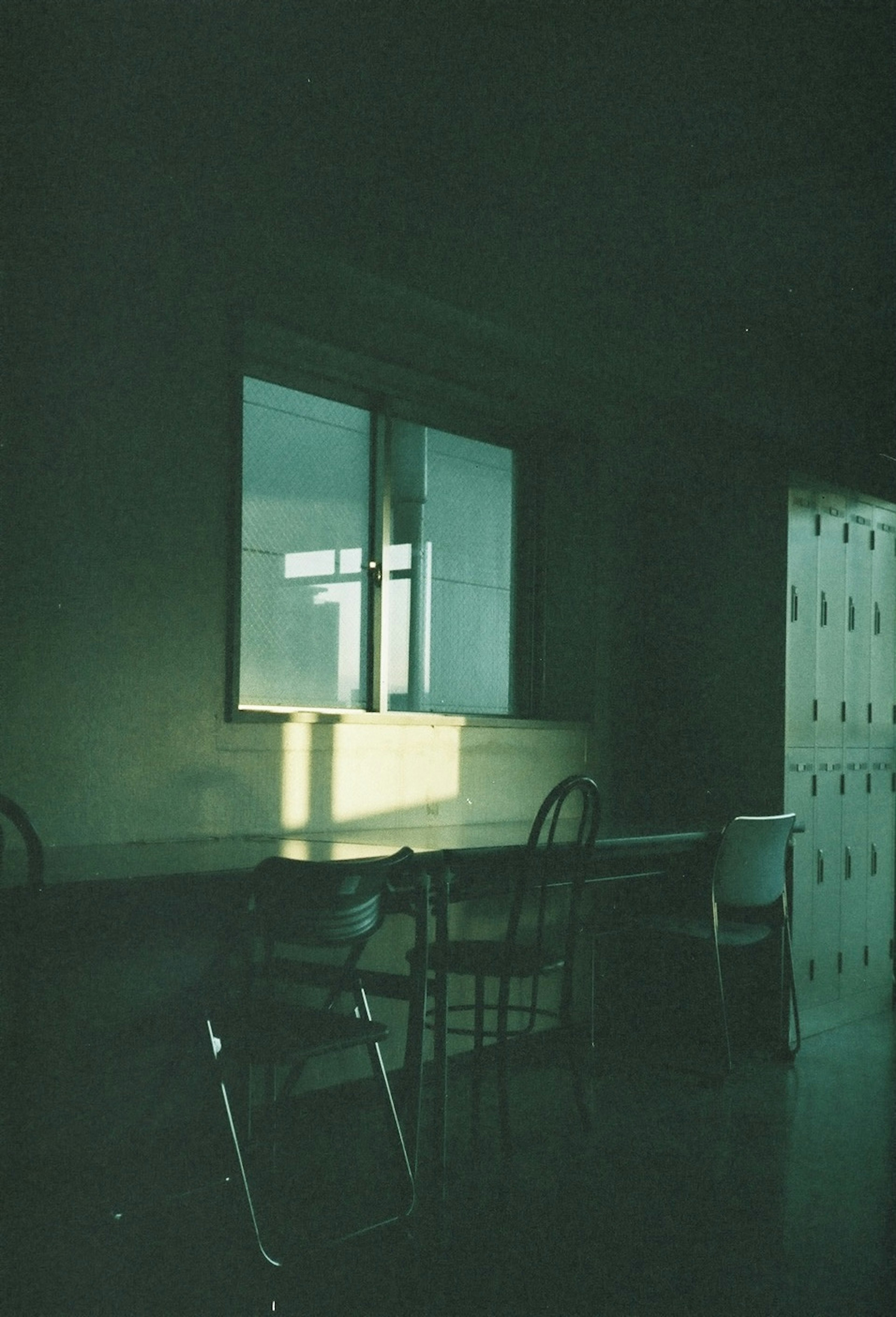 Silhouette of a table and chairs in a dimly lit room light streaming through a window