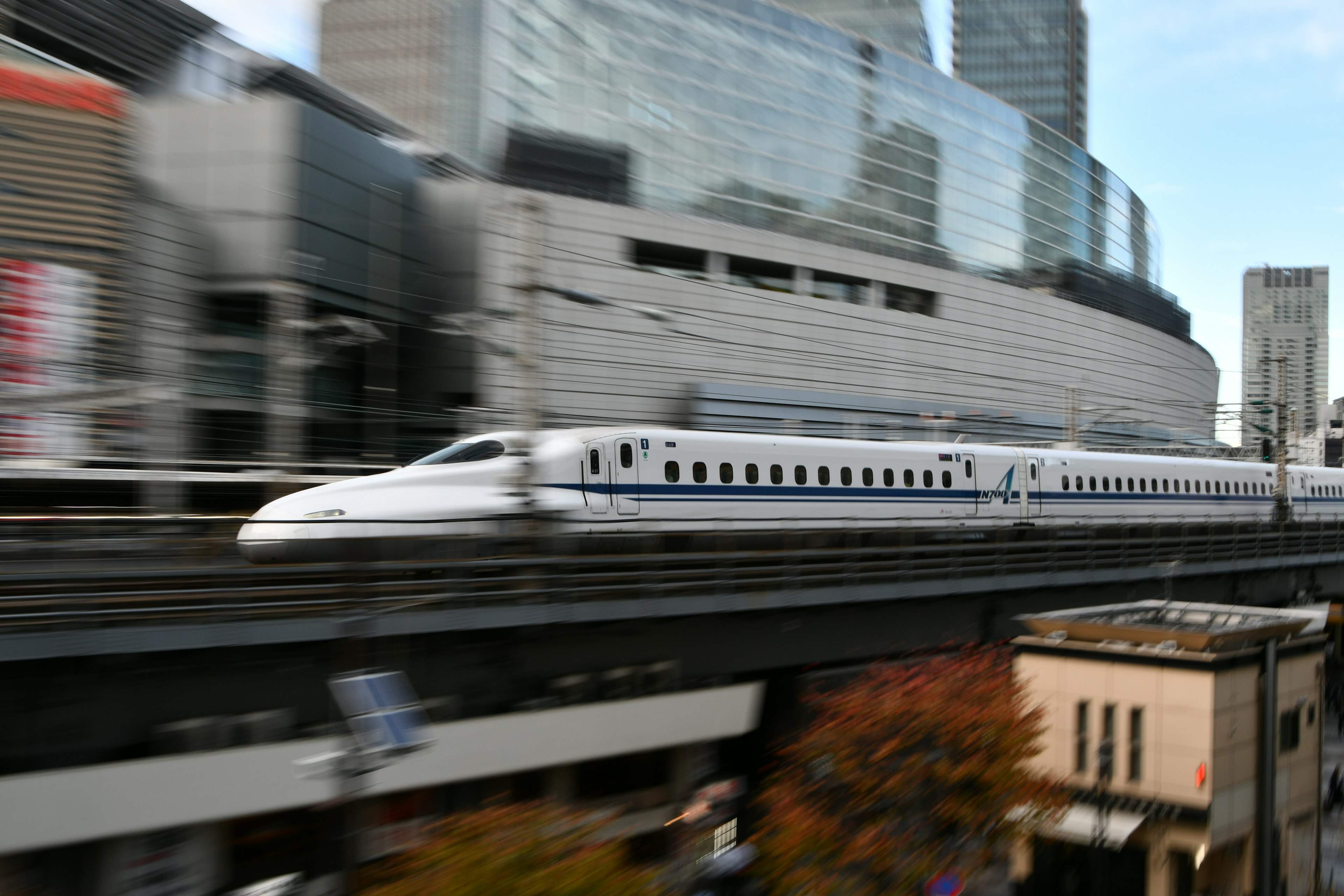 Shinkansen speeding through urban landscape with modern buildings