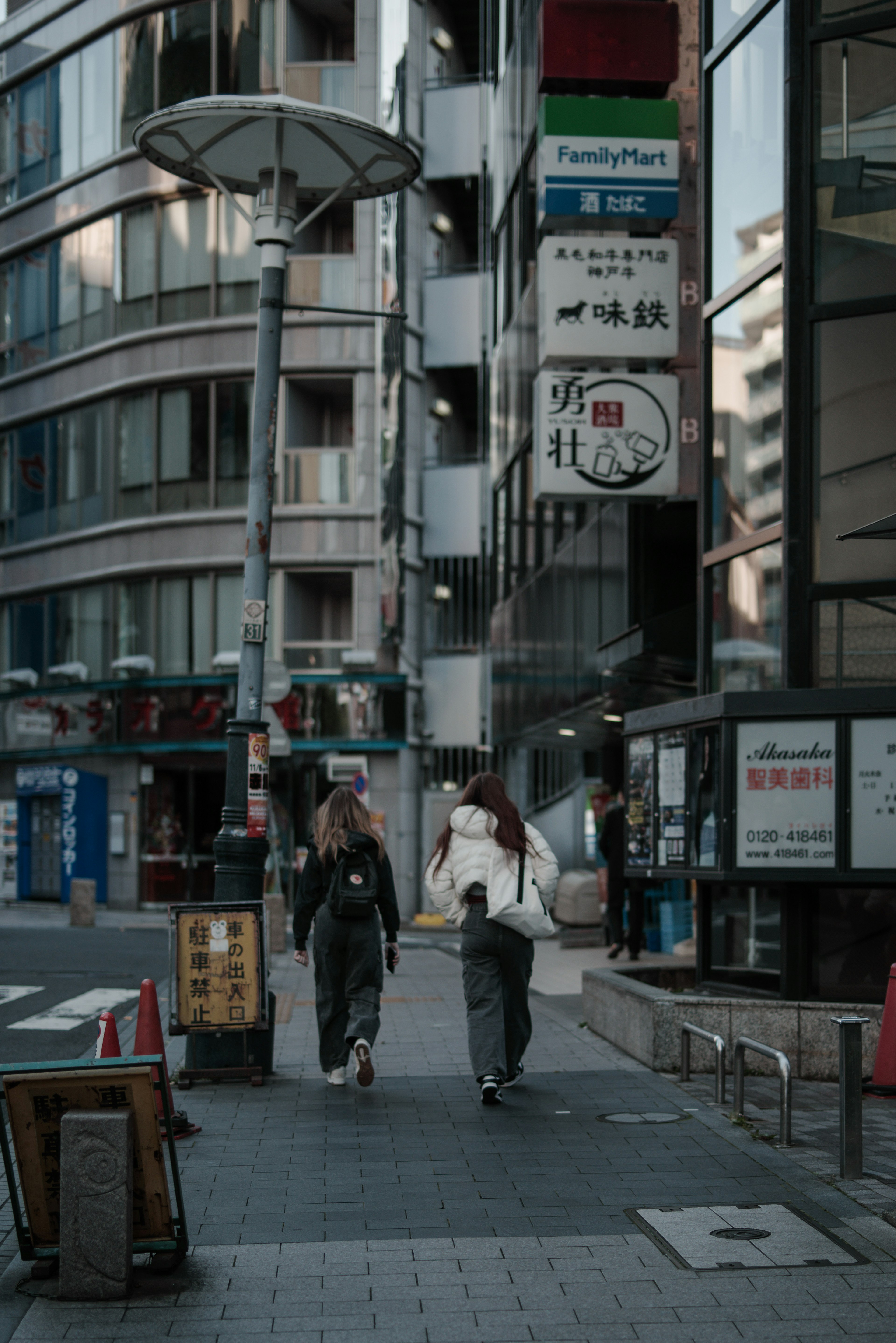 街を歩く二人の着物姿の女性と現代的なビルの背景