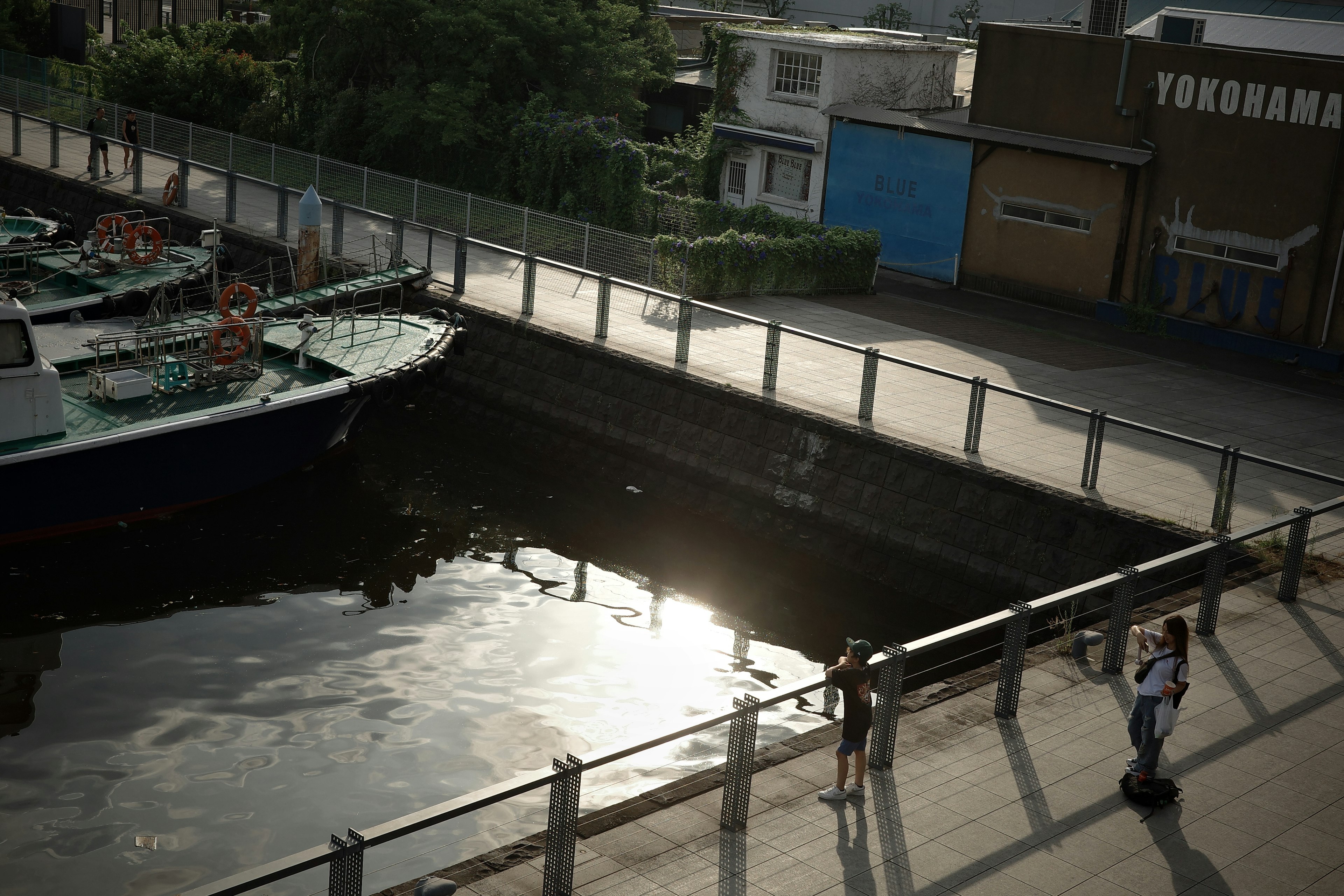 静かな水路に停泊する船と対岸の人々