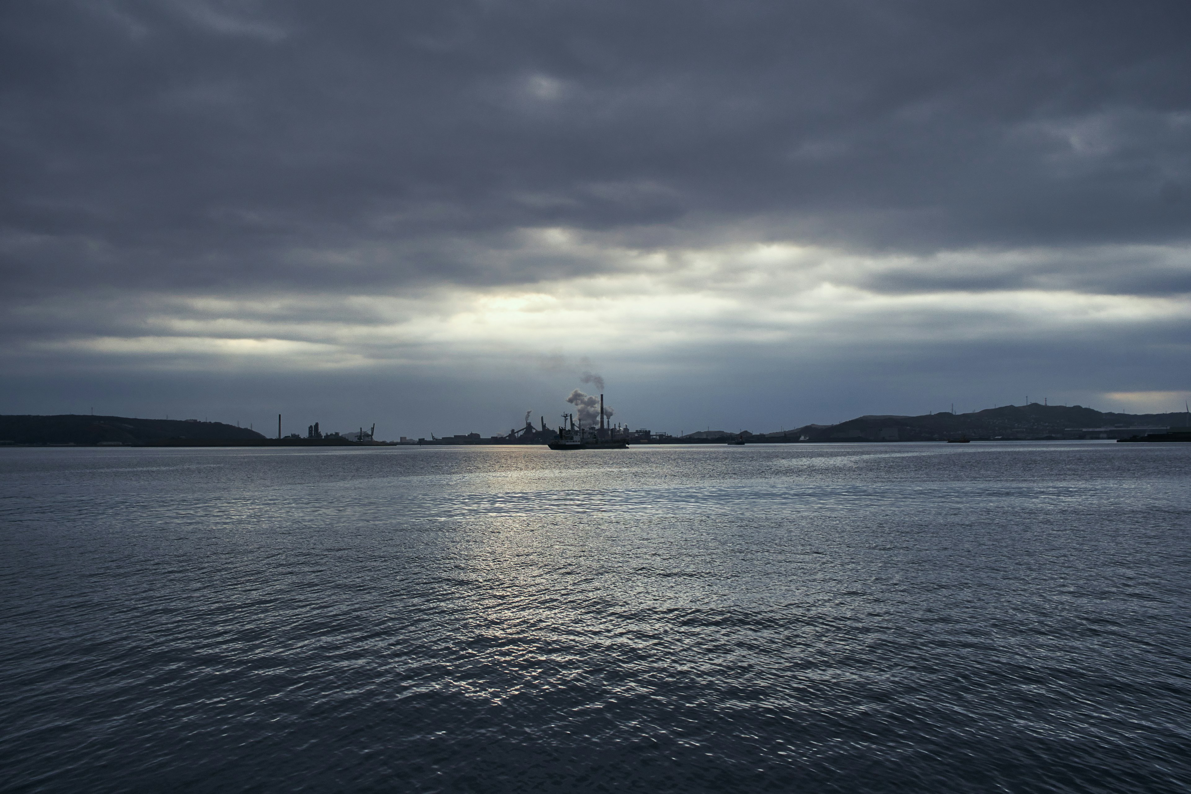 Vista serena del mar bajo un cielo oscuro con barcos a lo lejos