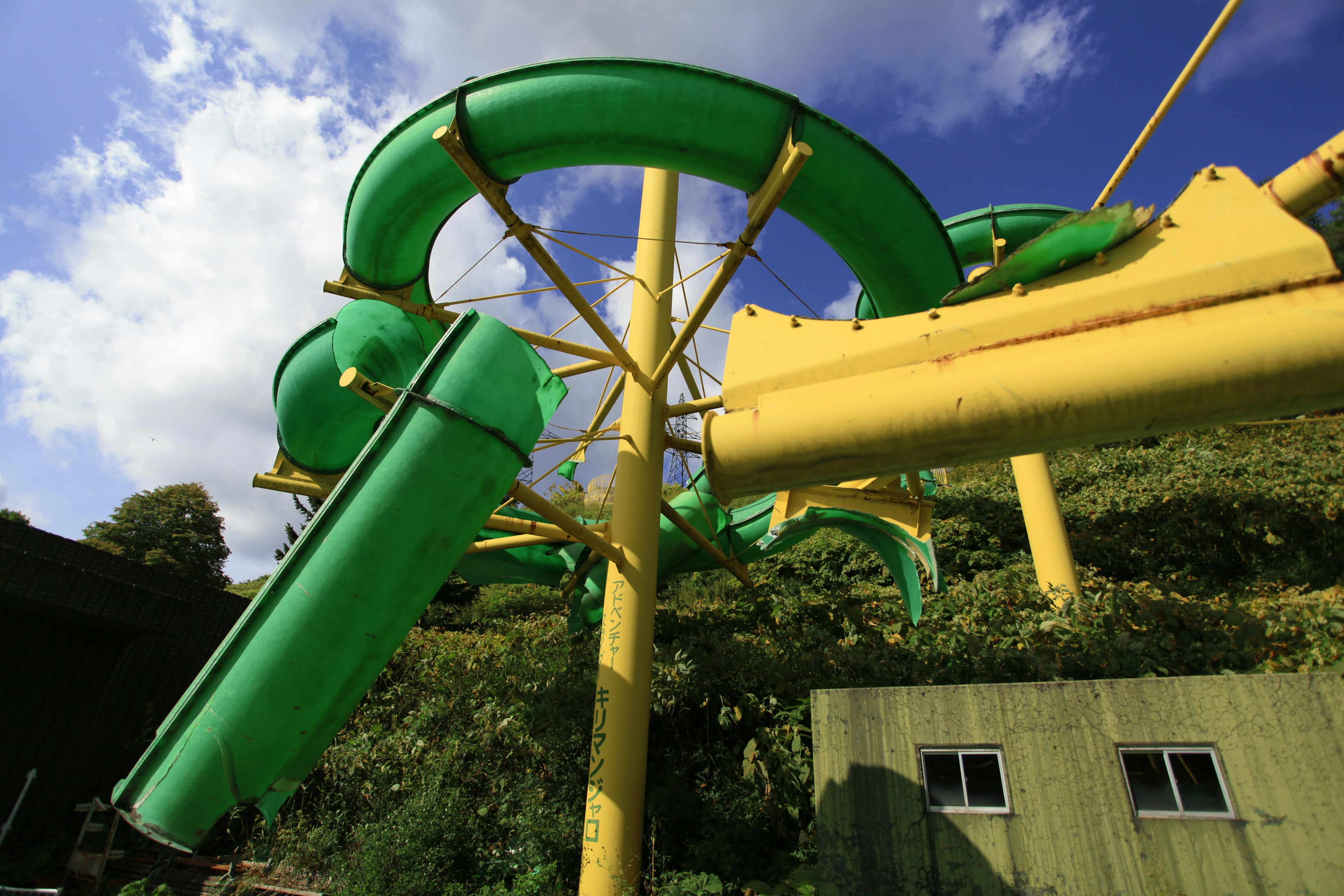 Green and yellow water slides in a theme park under a blue sky