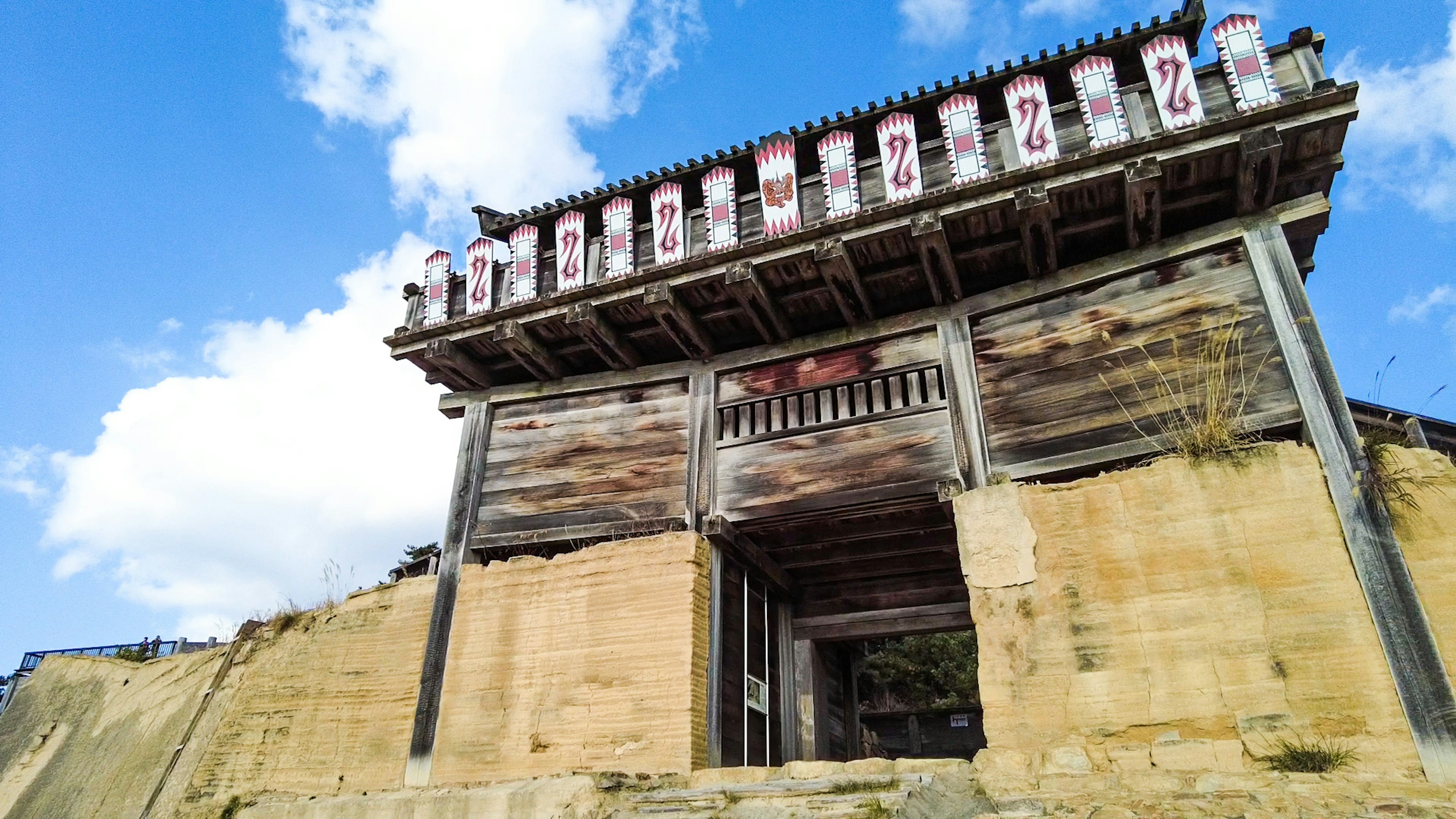 Ancient wooden gate structure against a blue sky