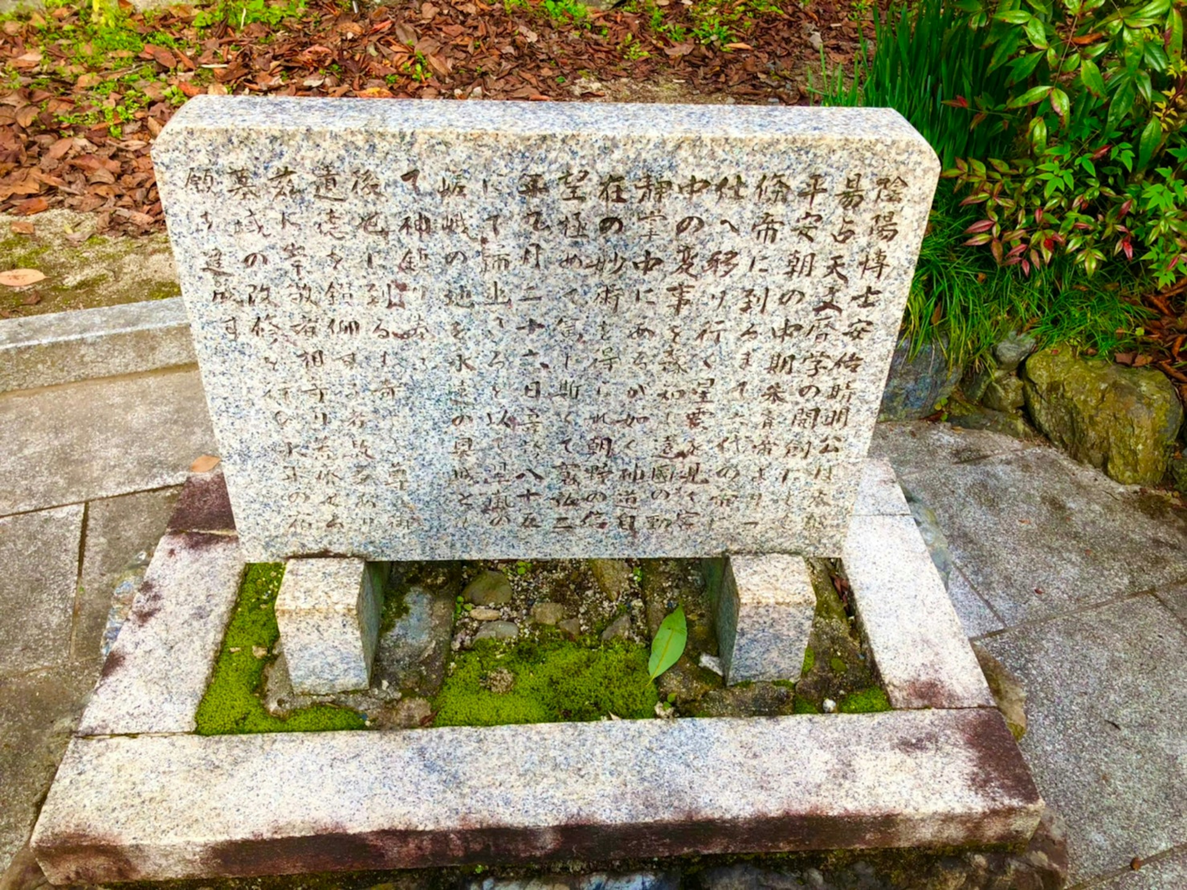 Tablette en granit avec inscriptions entourée de verdure