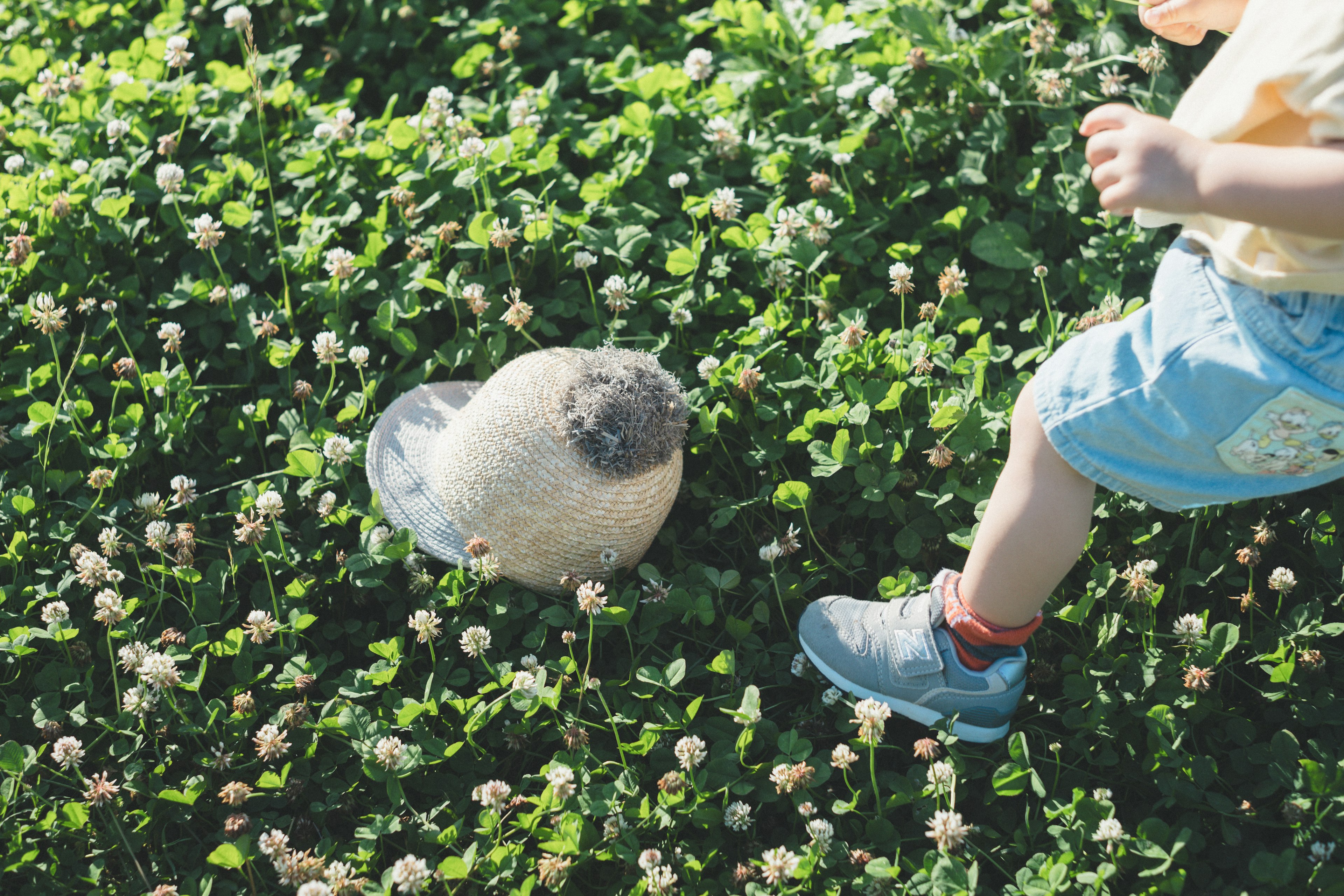 Ein Kinderfuß neben einem weißen Ball auf grünem Gras