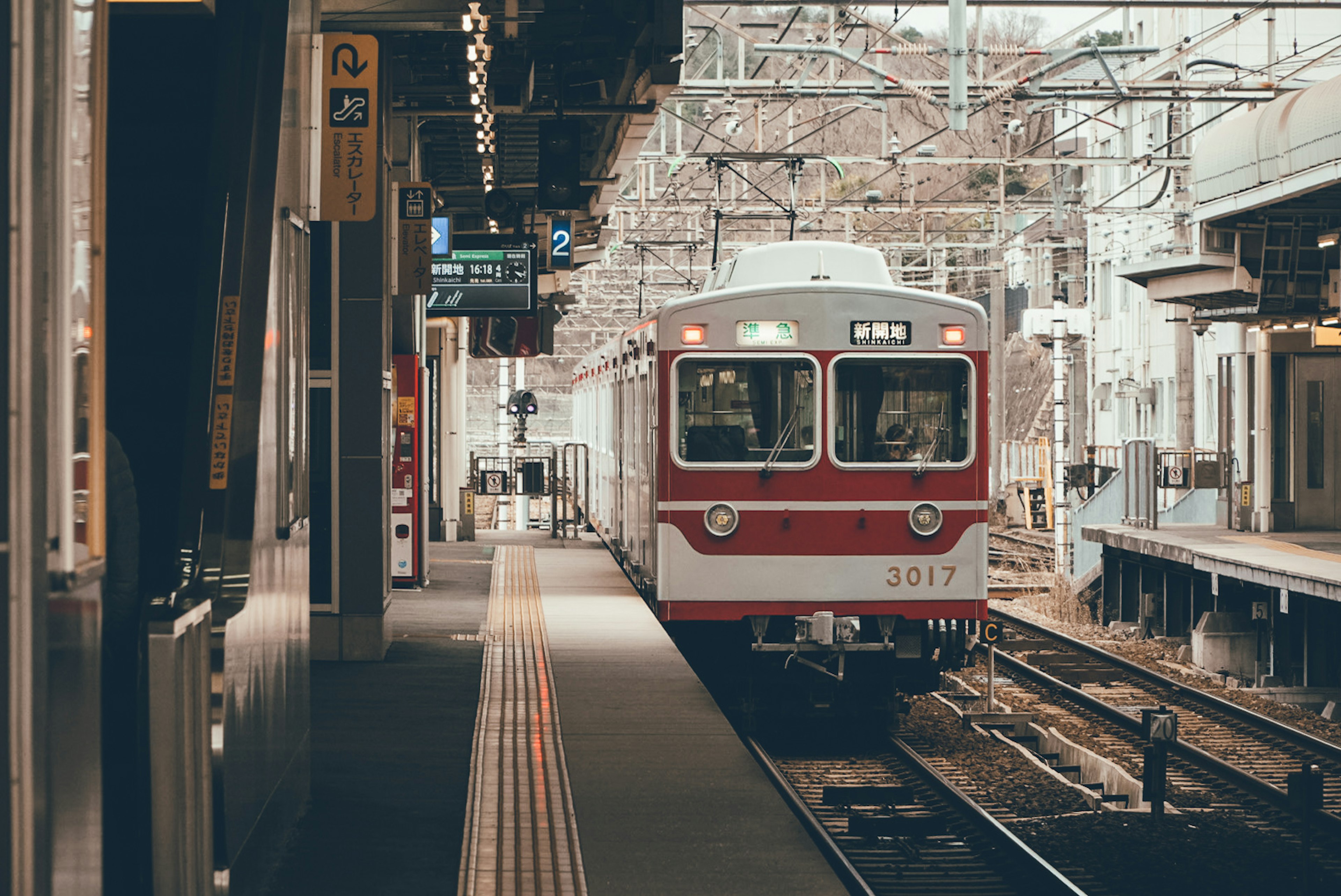 駅に停車中の赤い電車と線路の風景